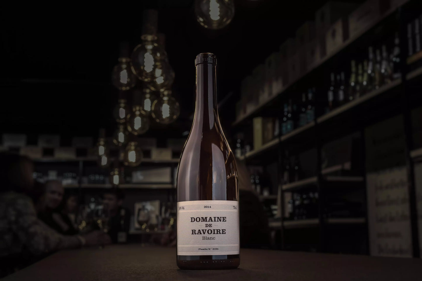 Flasche Domaine de Ravoire Blanc auf dem Tisch in der dunklen Vinothek Hauser.