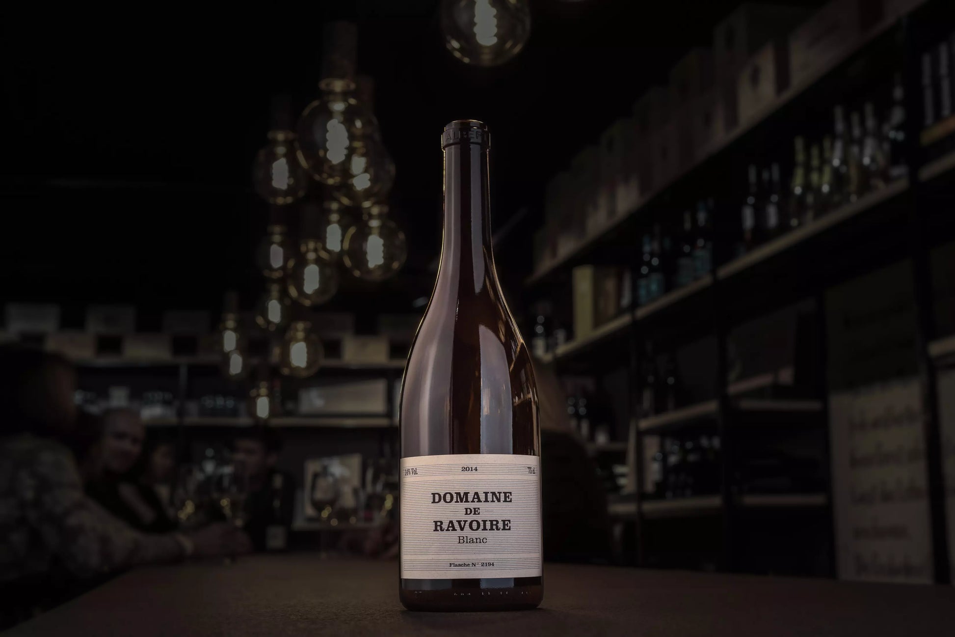 Flasche Domaine de Ravoire Blanc auf dem Tisch in der dunklen Vinothek Hauser.