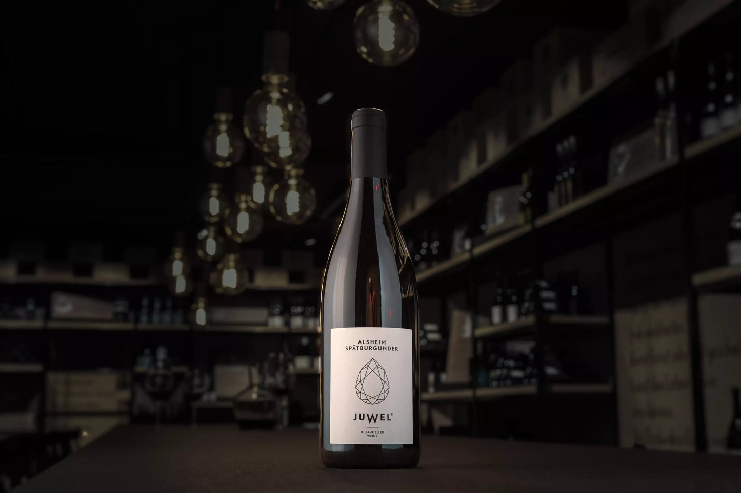 Flasche Alsheim Spätburgunder von Juwel Weine Juliane Eller auf dem Tisch in der dunklen Vinothek Hauser