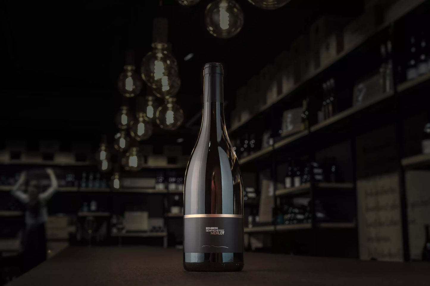 Eichberg Merlot von der Brunner Weinmanufaktur auf dem Tisch in der dunklen Vinothek Hauser.