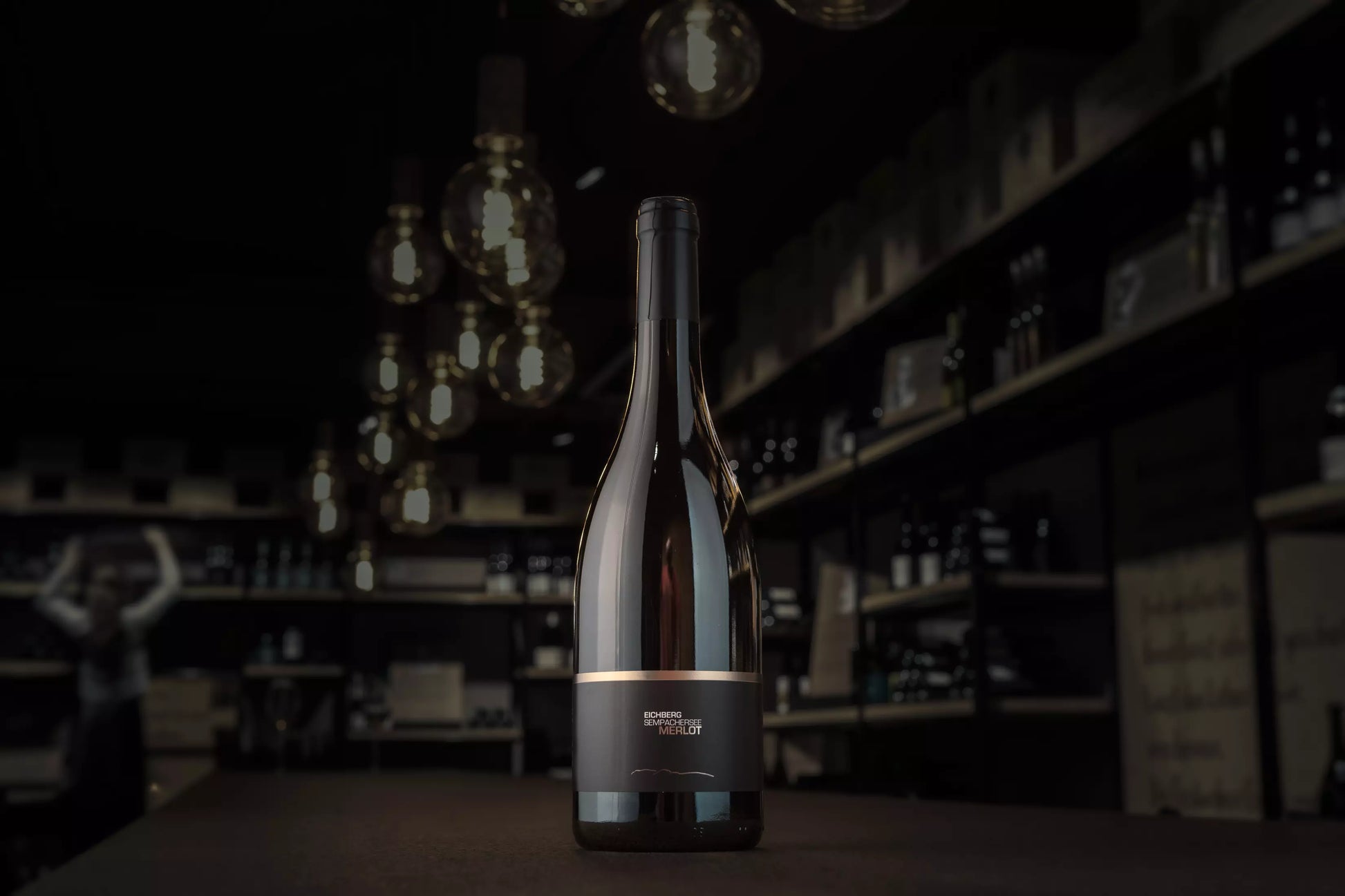 Eichberg Merlot von der Brunner Weinmanufaktur auf dem Tisch in der dunklen Vinothek Hauser.