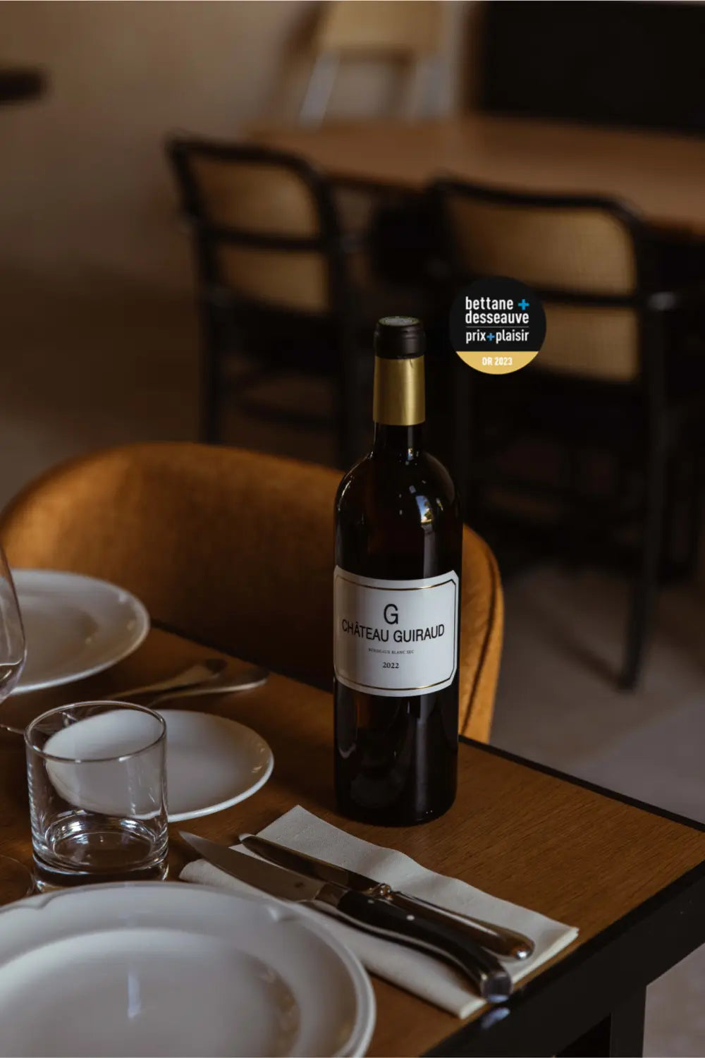 Flasche G de Château Guiraud auf einem gedeckten Tisch.