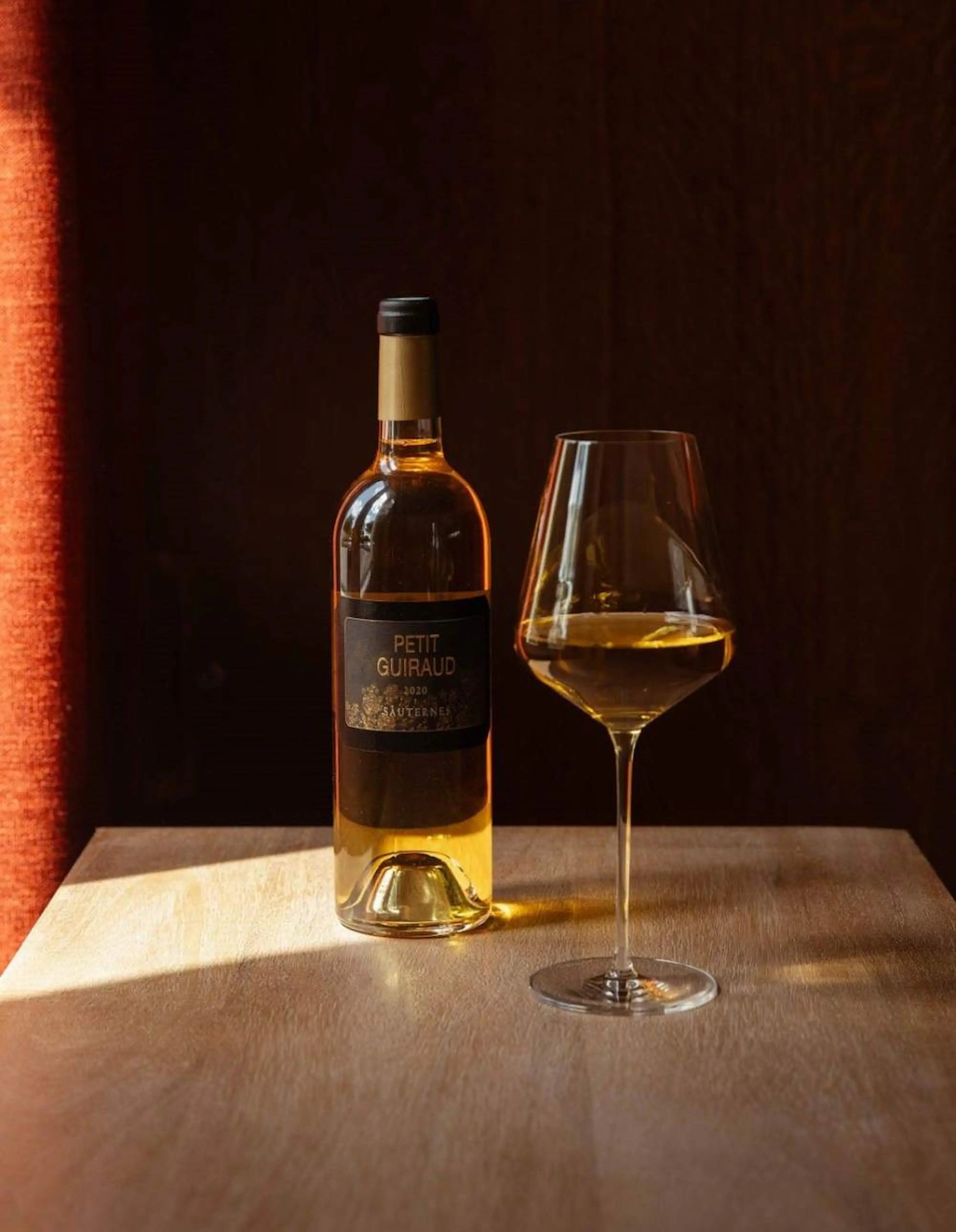 Petit Guiraud vom Château Guiraud mit einem eingeschenkten Glas auf einem Tisch.