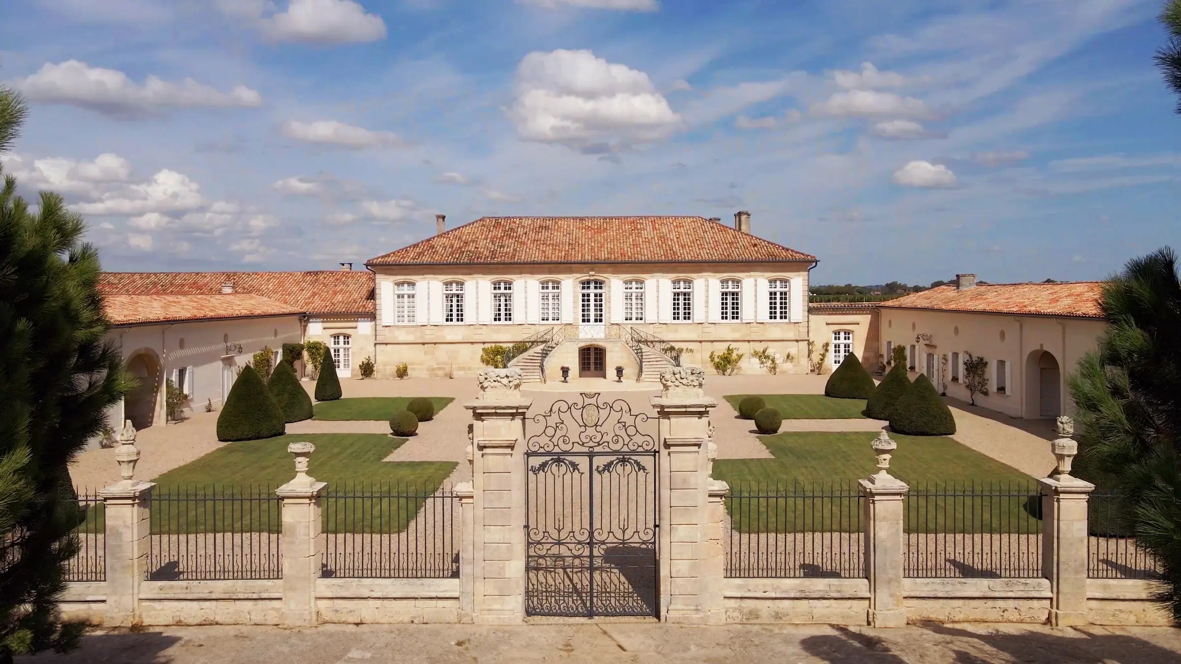 Aufnahme vom Eingang zu Château La Lagune mit Zaun und gusseisernem Tor davor.