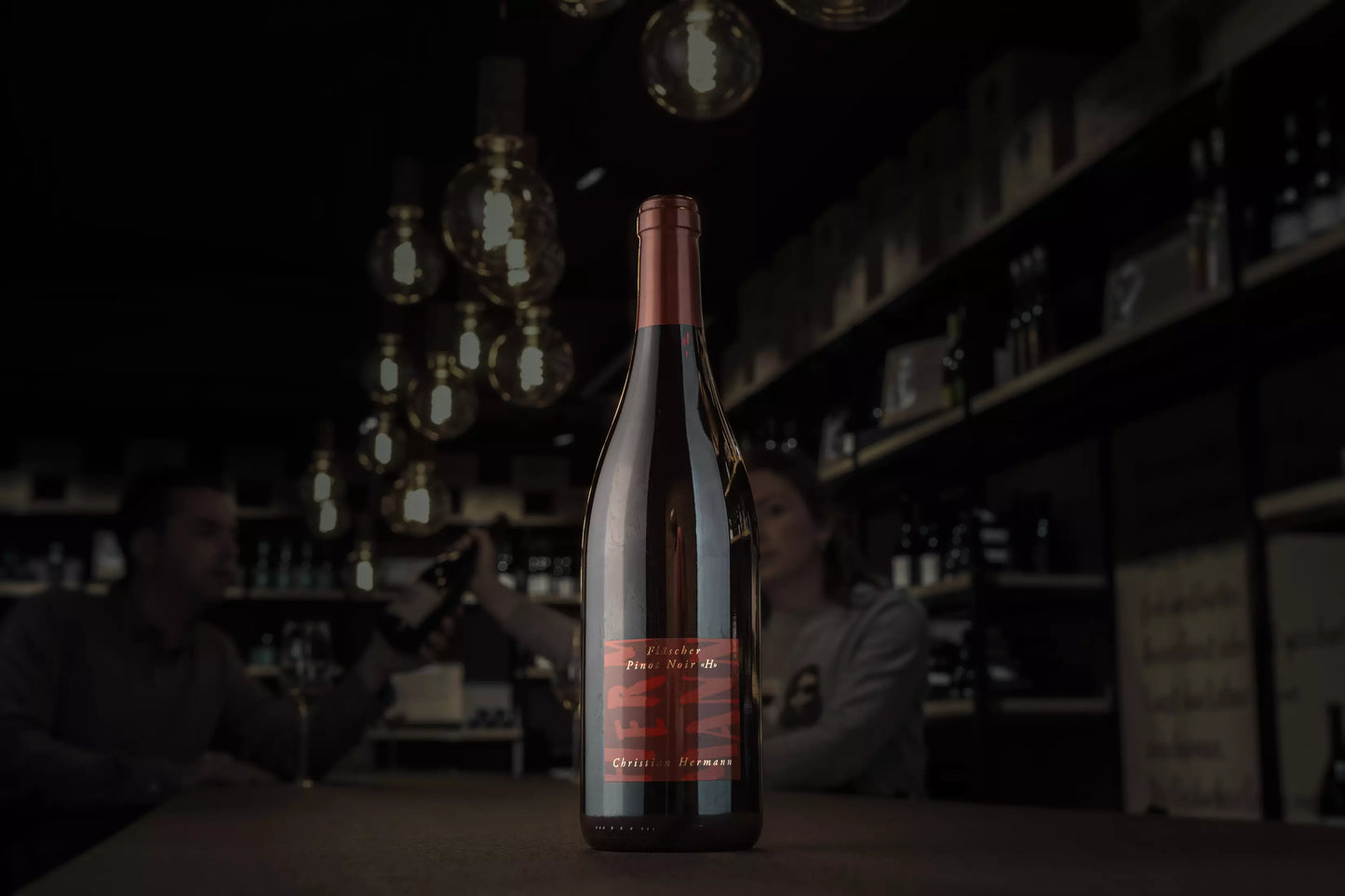 Fläscher Pinot Noir H von Christian Hermann in der dunklen Vinothek Hauser auf dem Tisch.