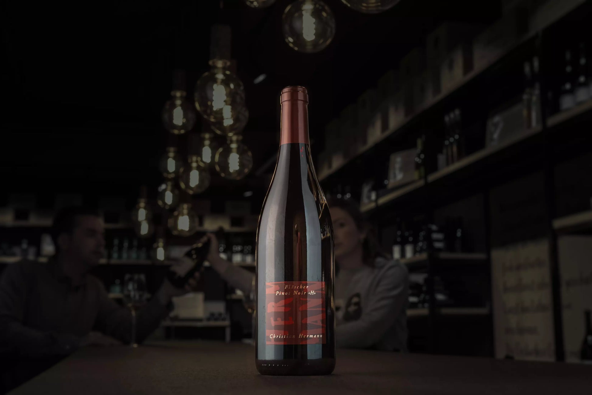 Fläscher Pinot Noir H von Christian Hermann in der dunklen Vinothek Hauser auf dem Tisch.
