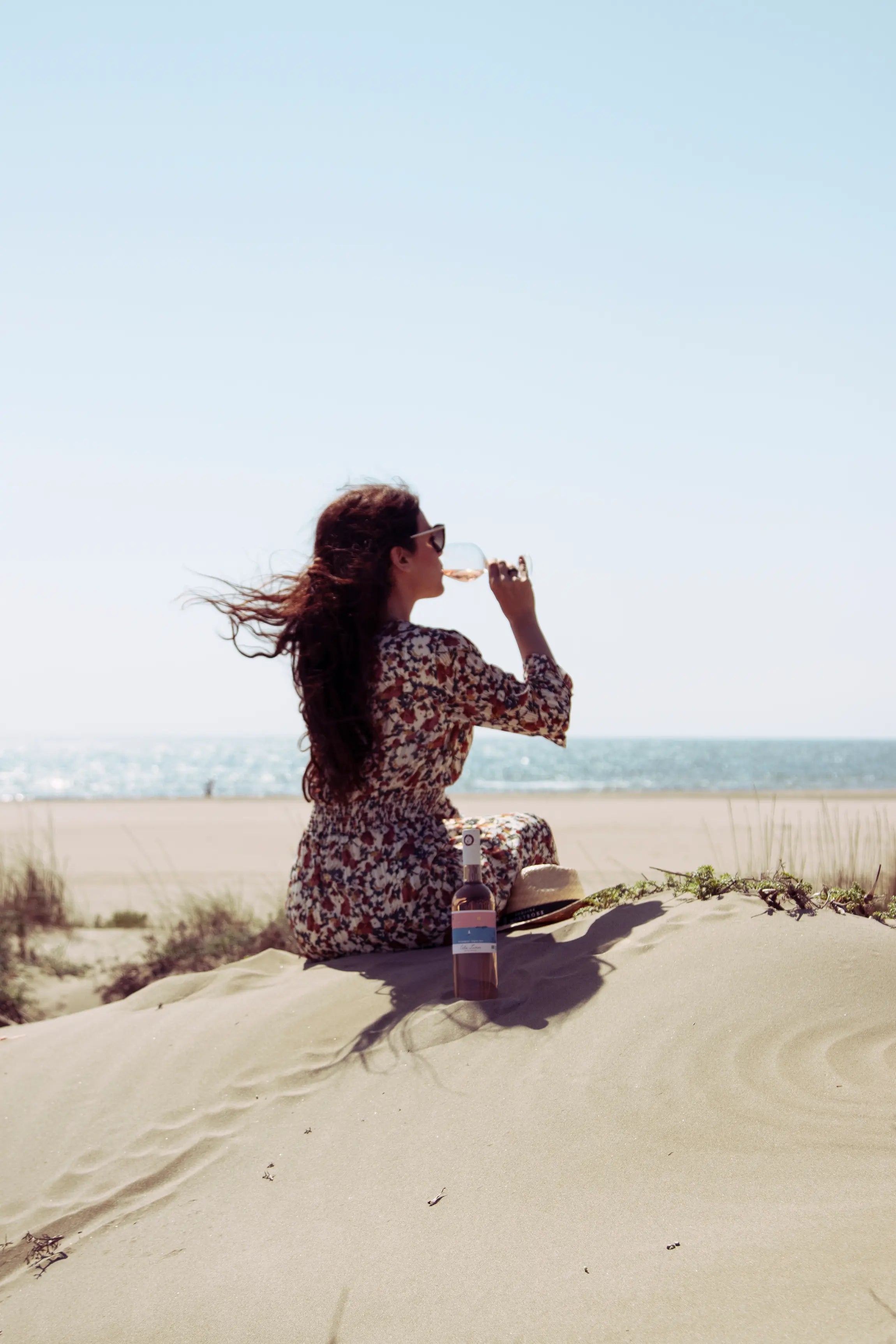 Frau am Strand im Languedoc mit einer Flasche Solis Lumen von der Domaine Montrose.