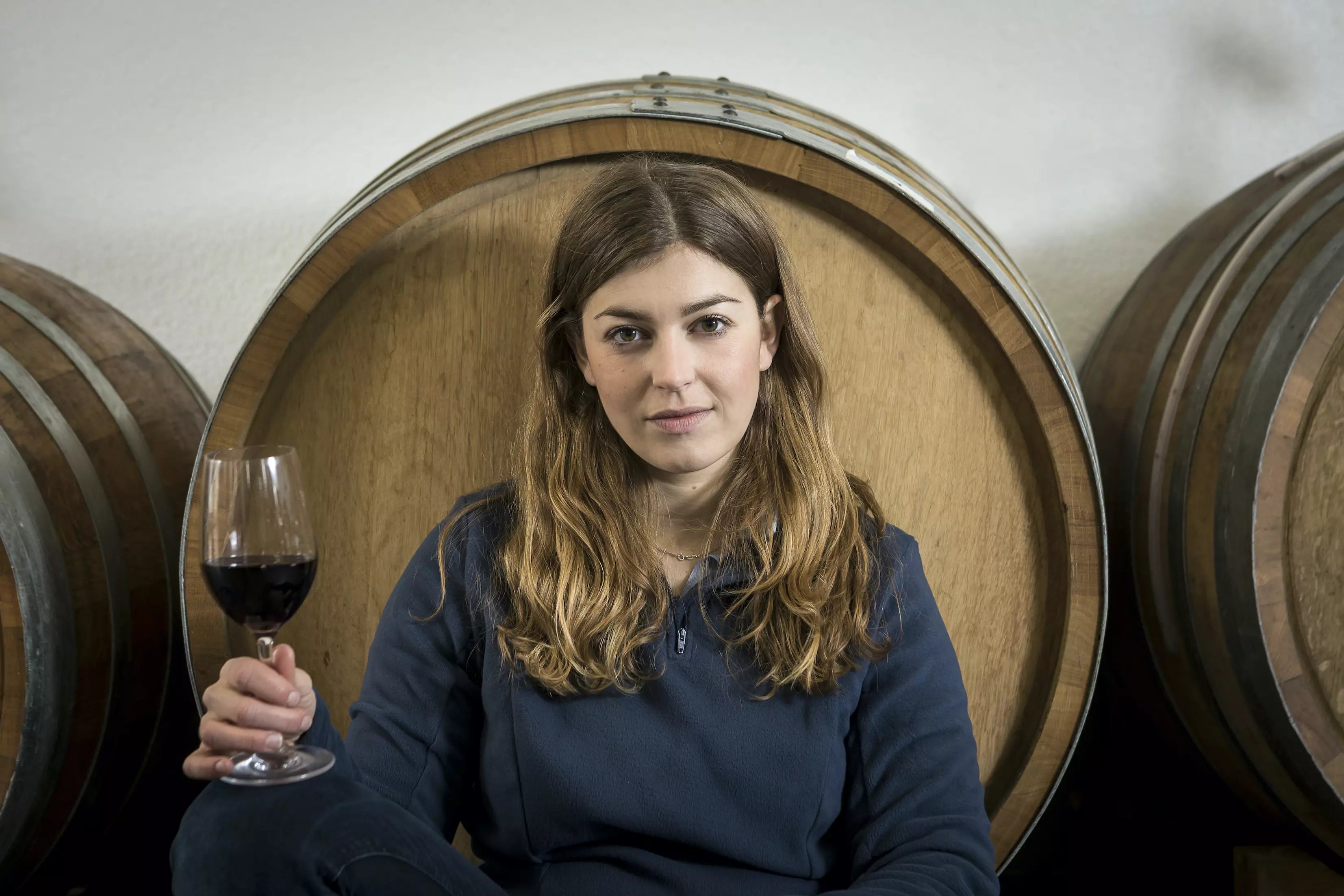 Portrait von Franziska Schömig vor Weinfässern im Keller vom Weingut Franziska Schömig.