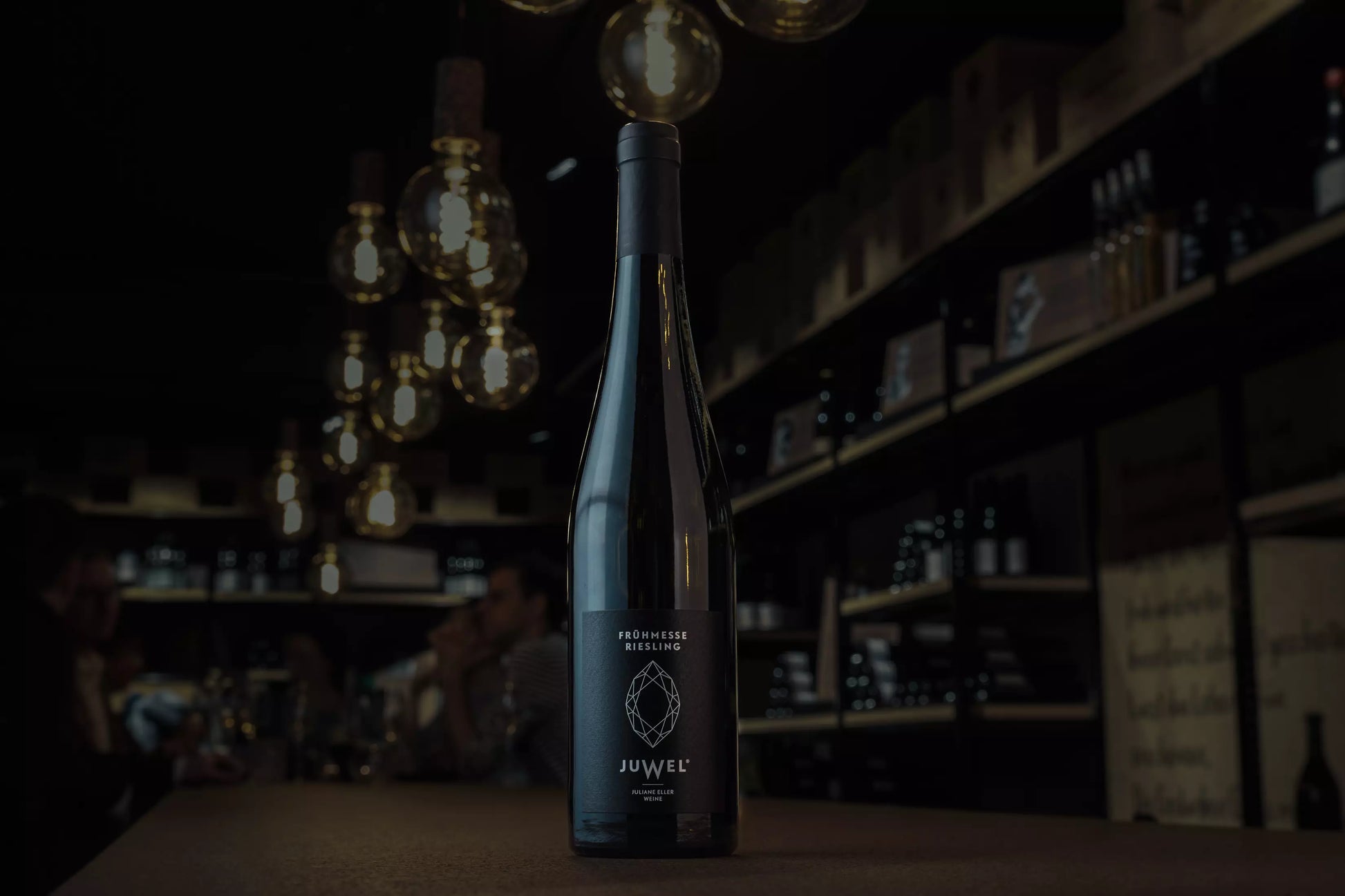 Flasche Frühmesse Riesling von Juwel Weine Juliane Eller auf dem Tisch in der dunklen Vinothek Hauser