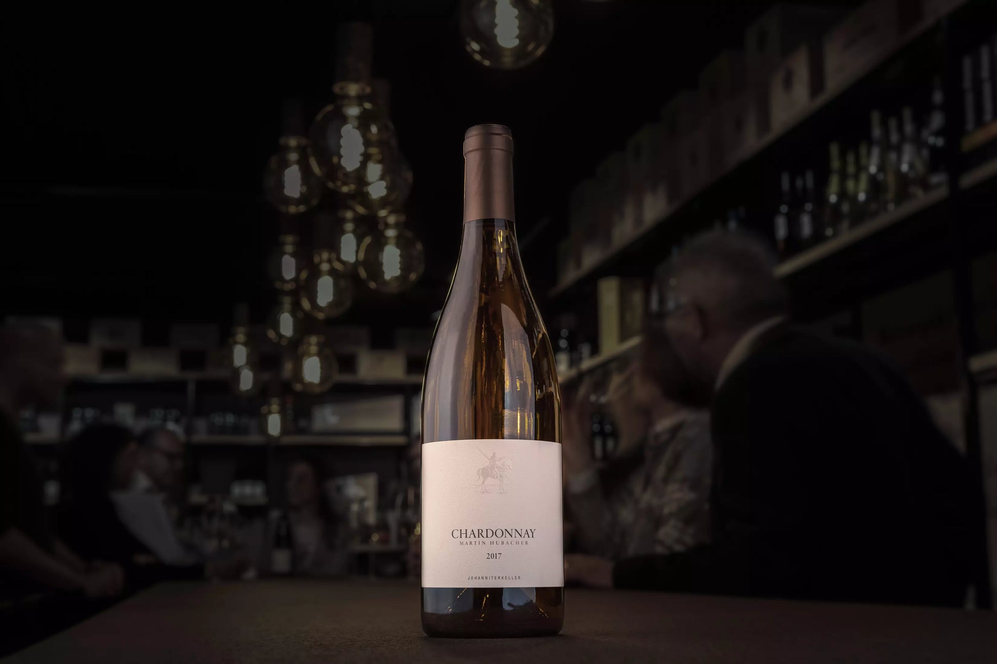 Chardonnay vom Johanniterkeller Martin Hubacher in der dunklen Vinothek Hauser auf dem Tisch.