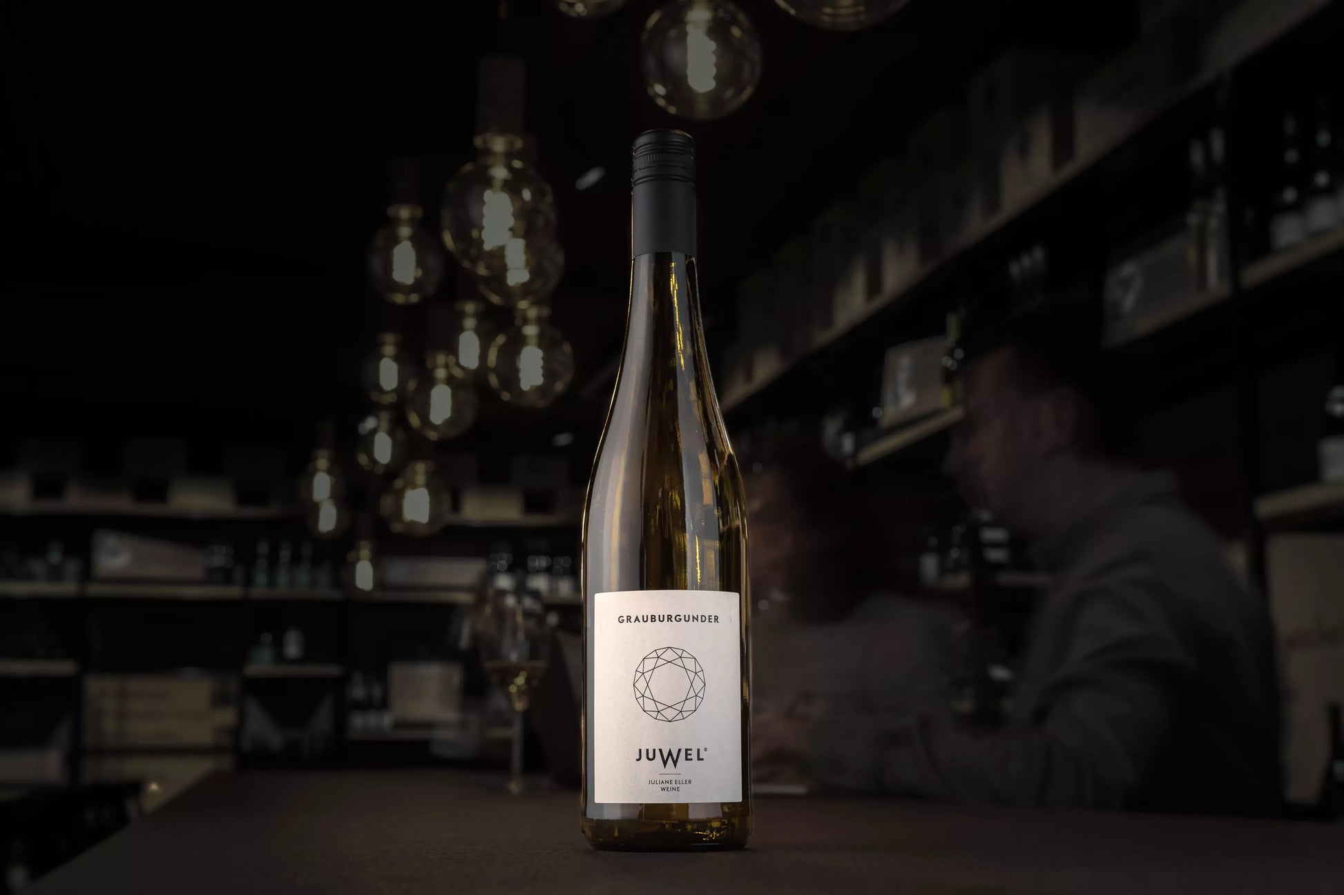 Flasche Juwel Grauburgunder auf dem Tisch in der dunklen Vinothek Hauser