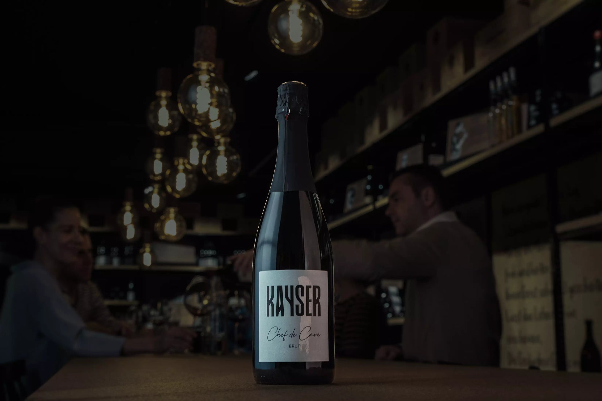 Chef de Cave Brut Rosé Sekt von Kayser Wein & Sekt auf dem Tisch in der dunklen Vinothek Hauser.