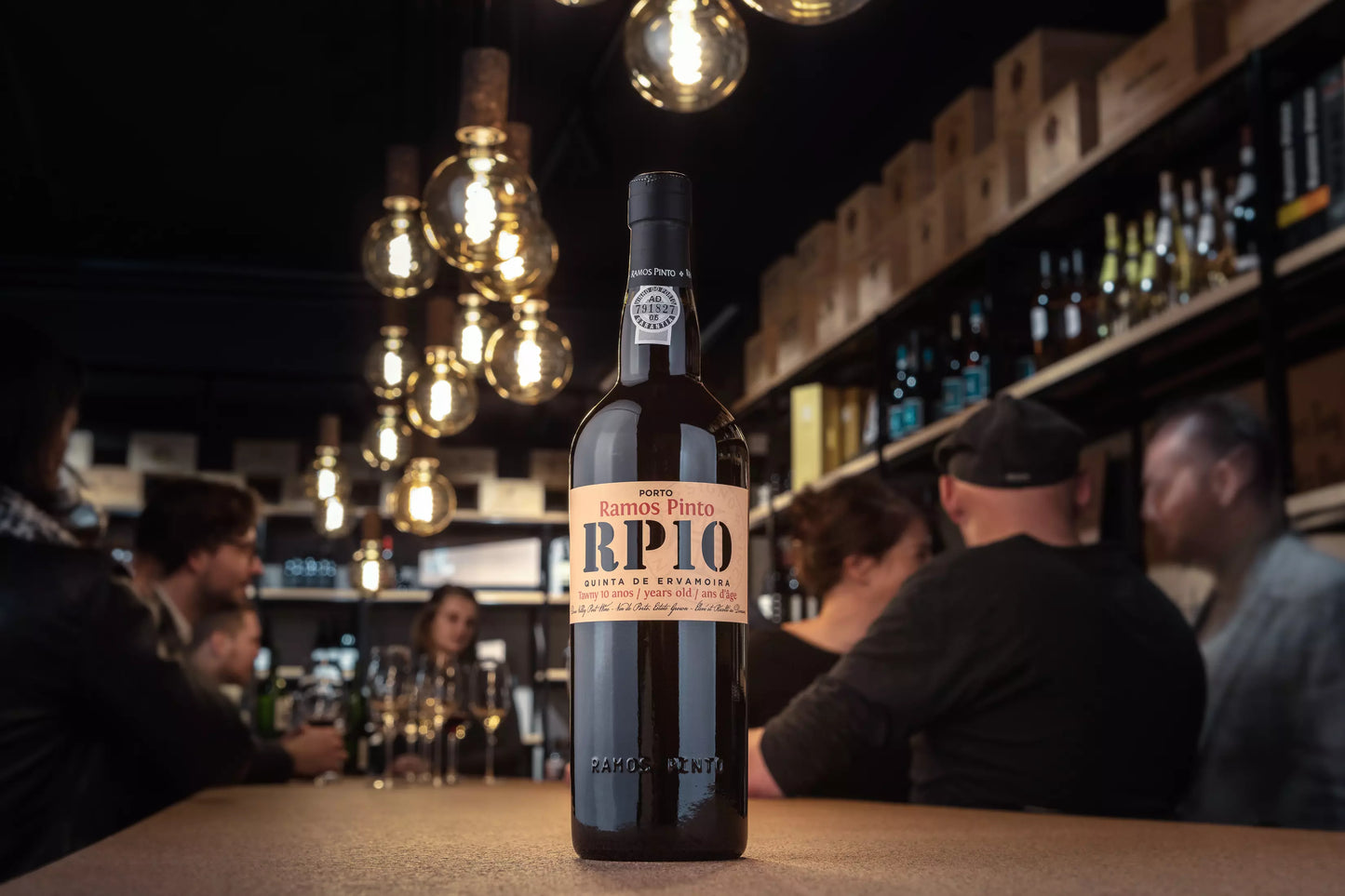 Flasche Porto 10 years von Ramos Pinto auf dem Tisch in der Vinothek Hauser mit einem Apéro, der im Hintergrund stattfindet.