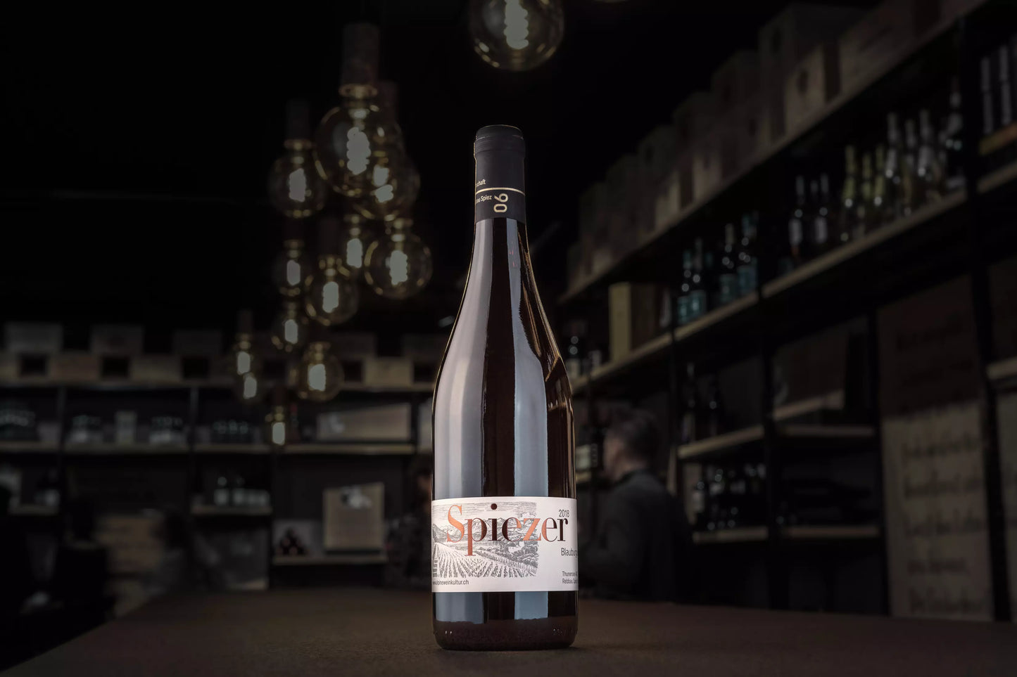 Spiezer Blauburgunder von Alpine Weinkultur Spiez auf dem Tisch in der dunklen Vinothek Hauser.