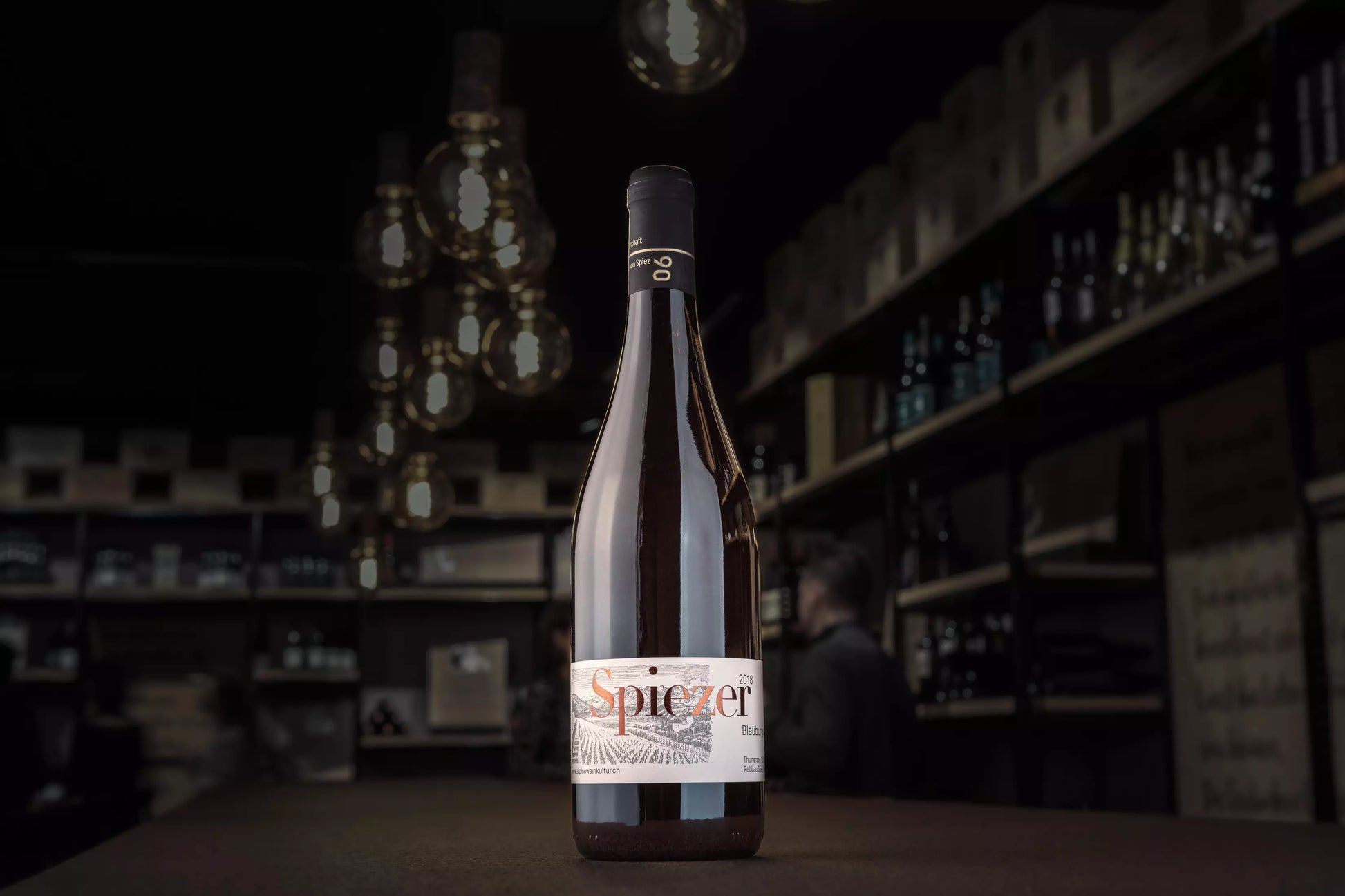 Spiezer Blauburgunder von Alpine Weinkultur Spiez auf dem Tisch in der dunklen Vinothek Hauser.