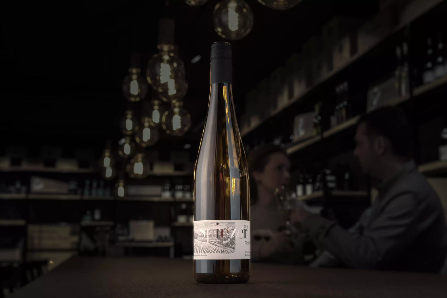 Spiezer Riesling-Sylvaner von Alpine Weinkultur Spiez auf dem Tisch in der dunklen Vinothek Hauser.