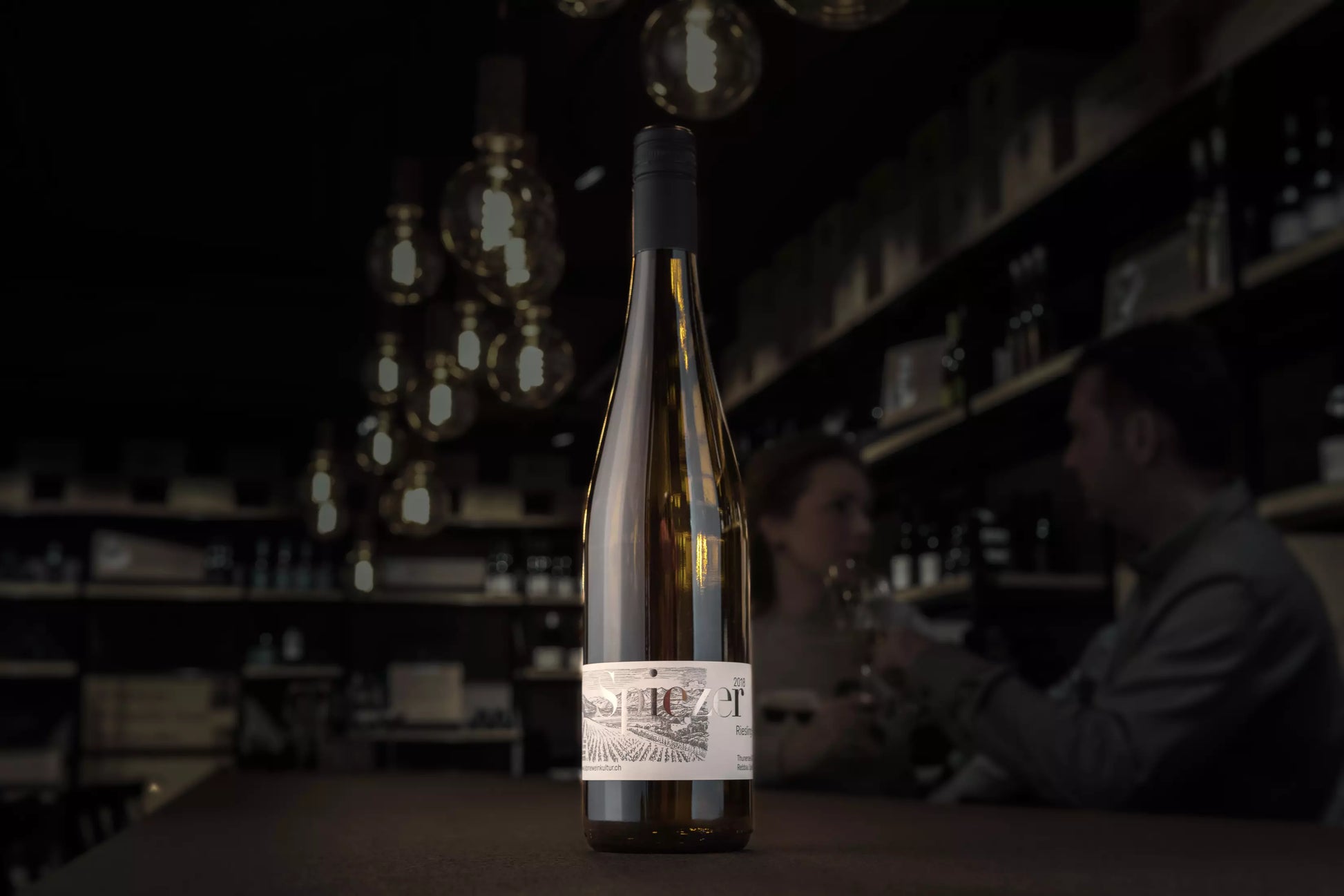 Spiezer Riesling-Sylvaner von Alpine Weinkultur Spiez auf dem Tisch in der dunklen Vinothek Hauser.