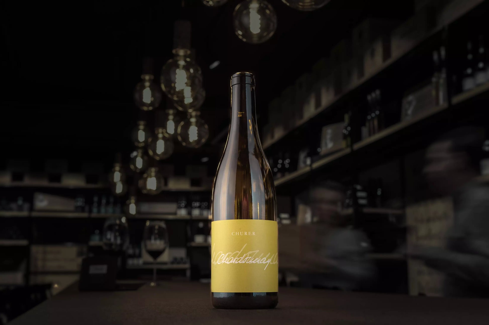 Churer Chardonnay in der dunklen Vinothek Hauser auf dem Tisch präsentiert.