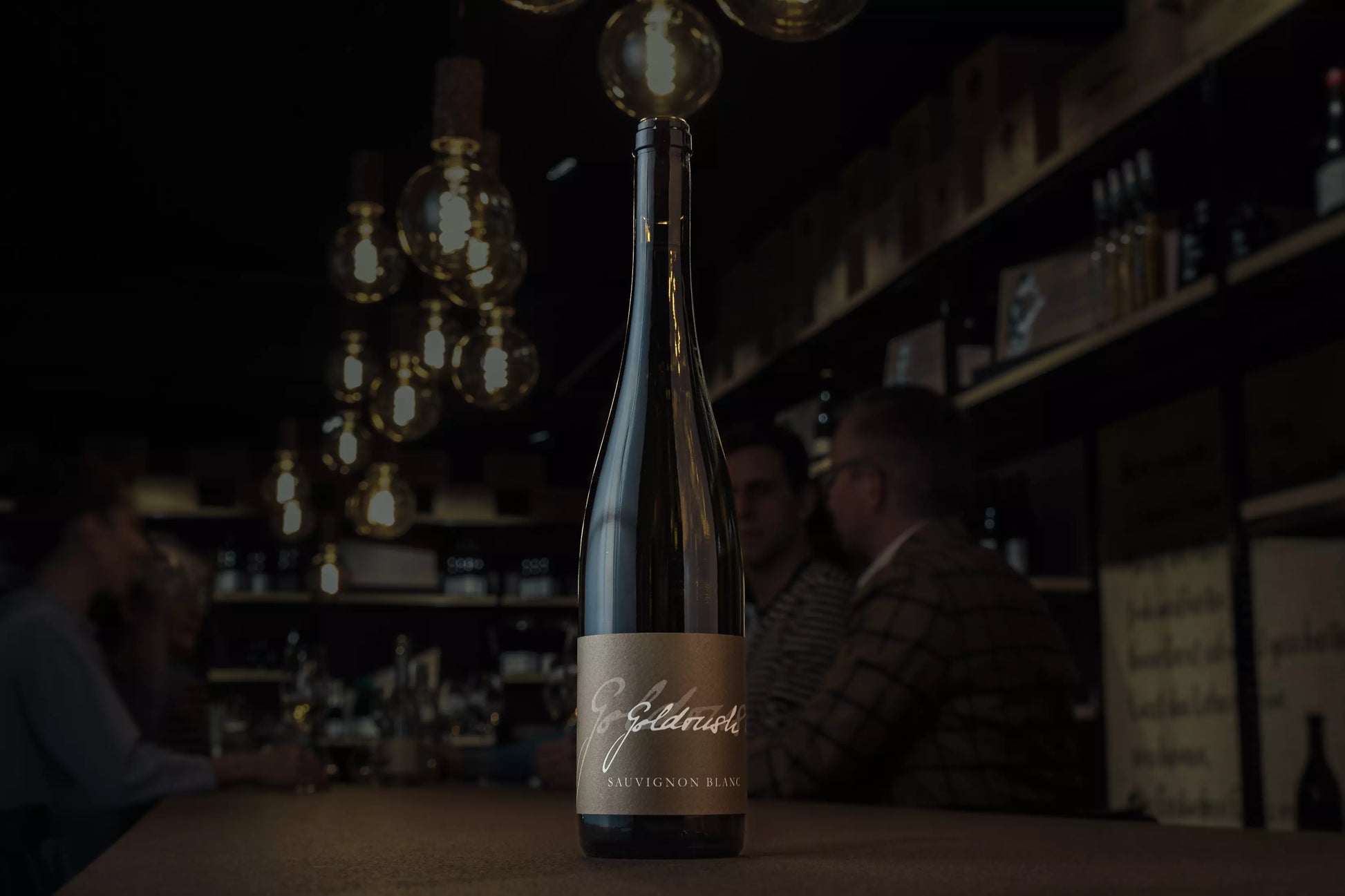 Goldrusch Sauvignon Blanc auf dem Tisch in der dunklen Vinothek Hauser im Fokus.