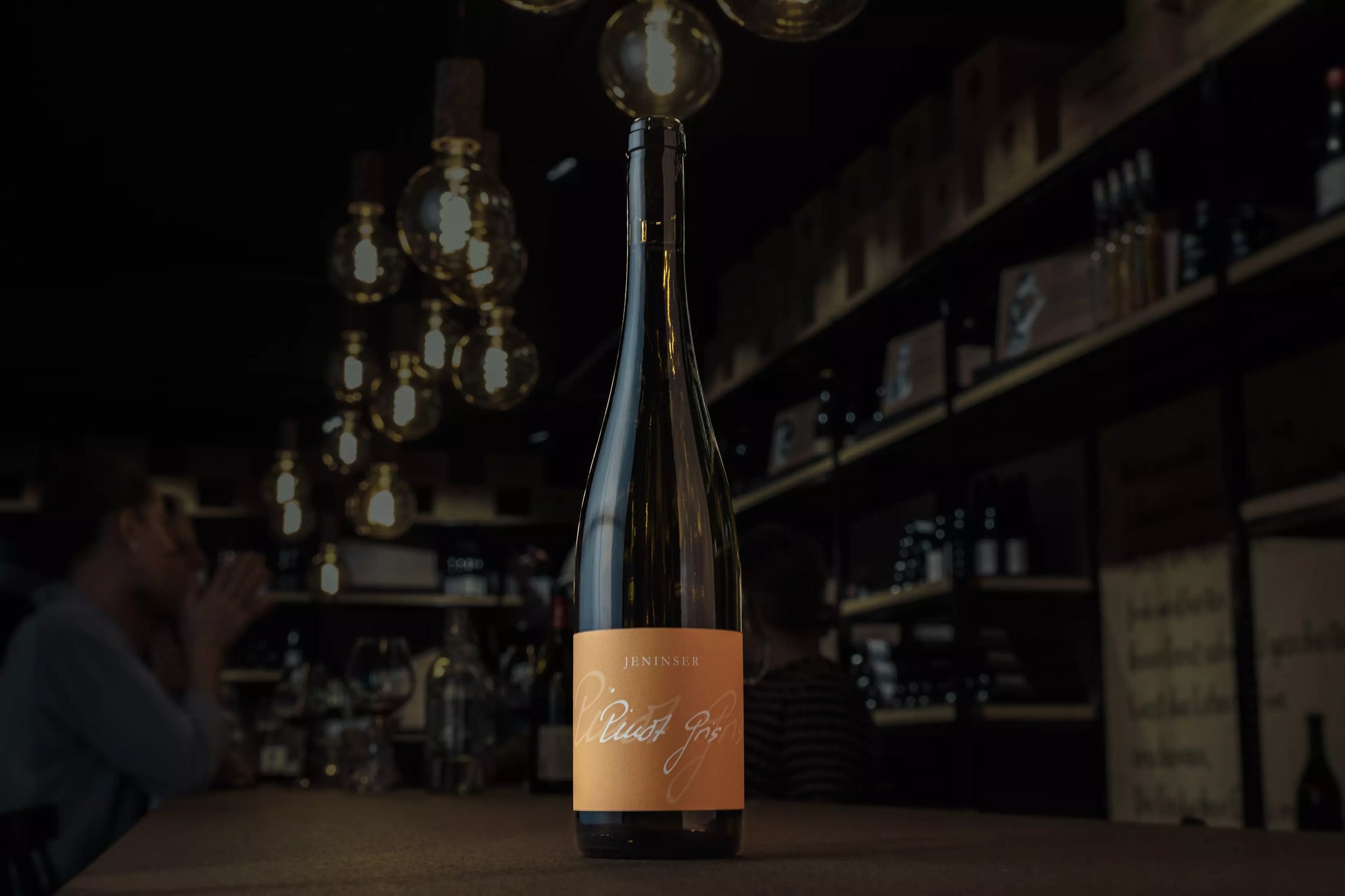 Jeninser Pinot Gris in der dunklen Vinothek Hauser auf dem Tisch präsentiert.