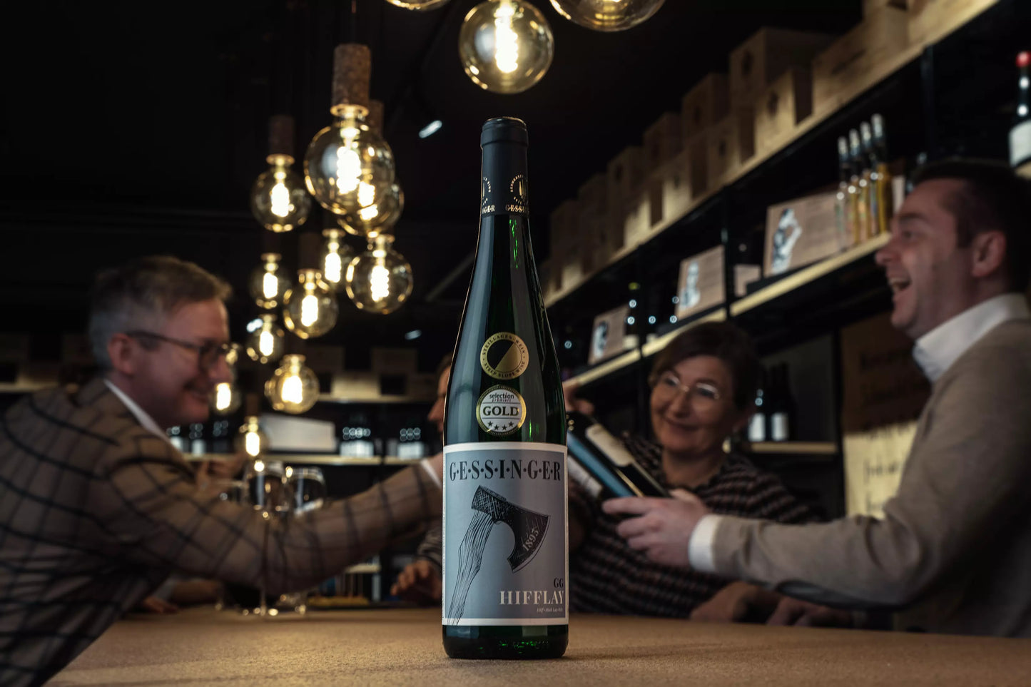 Zeltinger Sonnenuhr Hifflay Riesling Grosses Gewächs in der Vinothek Hauser auf dem Tisch it Gästen im Hintergrund.