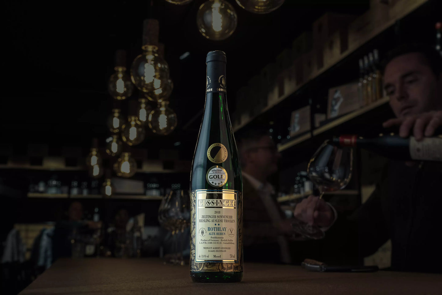 Zeltinger Sonnenuhr Riesling Auslese trocken vom Weingut A. Gessinger auf dem Tisch in der dunklen Vinothek Hauser.