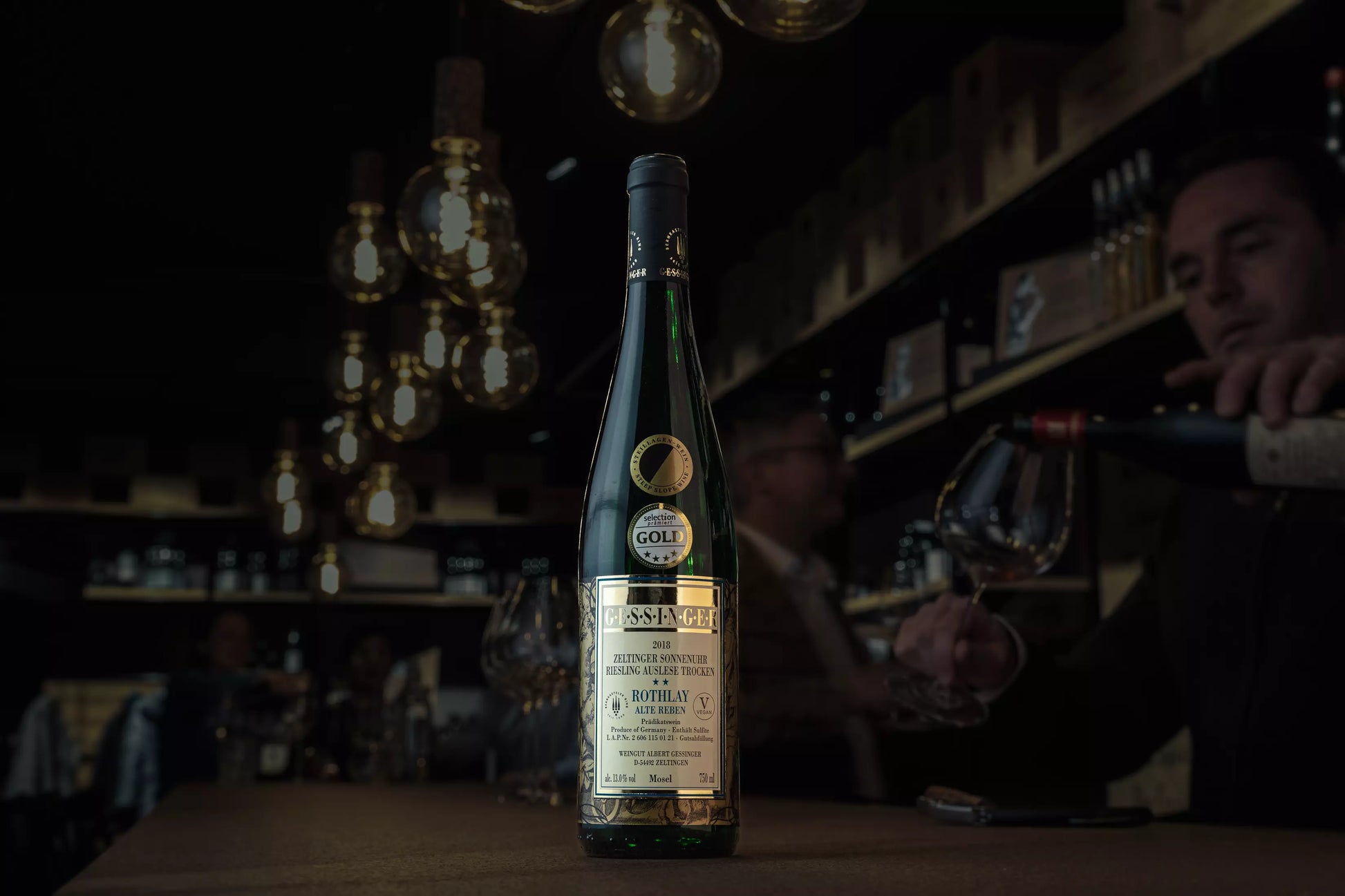 Zeltinger Sonnenuhr Riesling Auslese trocken vom Weingut A. Gessinger auf dem Tisch in der dunklen Vinothek Hauser.