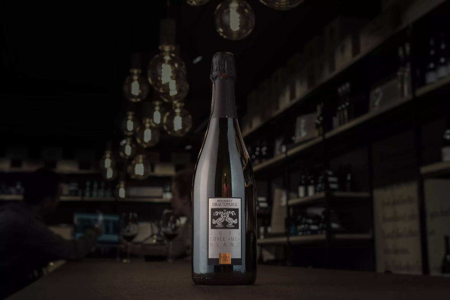 Cuvée MC Blanc vom Weingut Drautz-Able auf dem Tisch in der dunklen Vinothek Hauser.