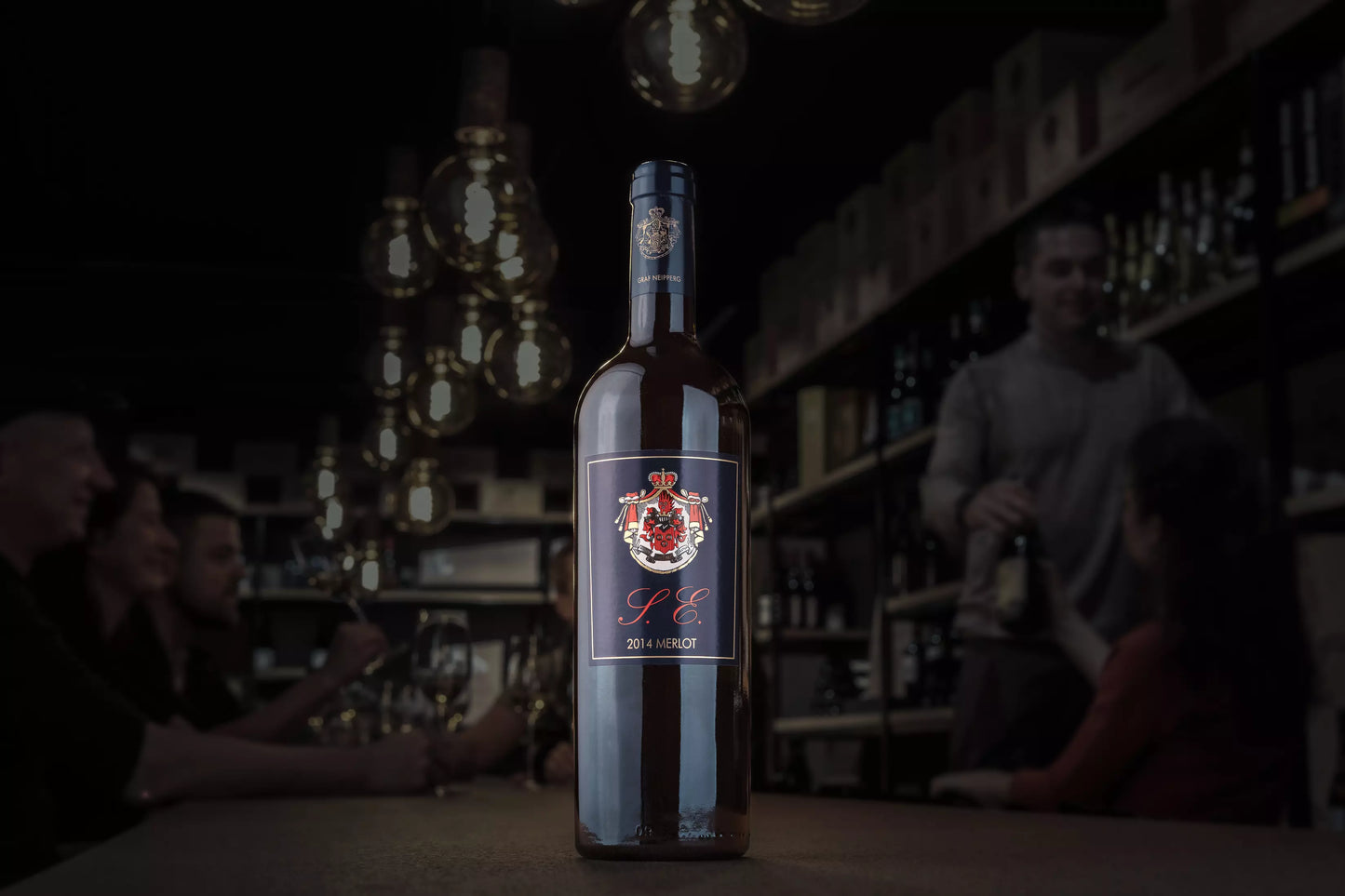 Dunkle Vinothek Hauser mit einer Flasche Merlot S.E. vom Weingut Graf Neipperg auf dem Tisch.