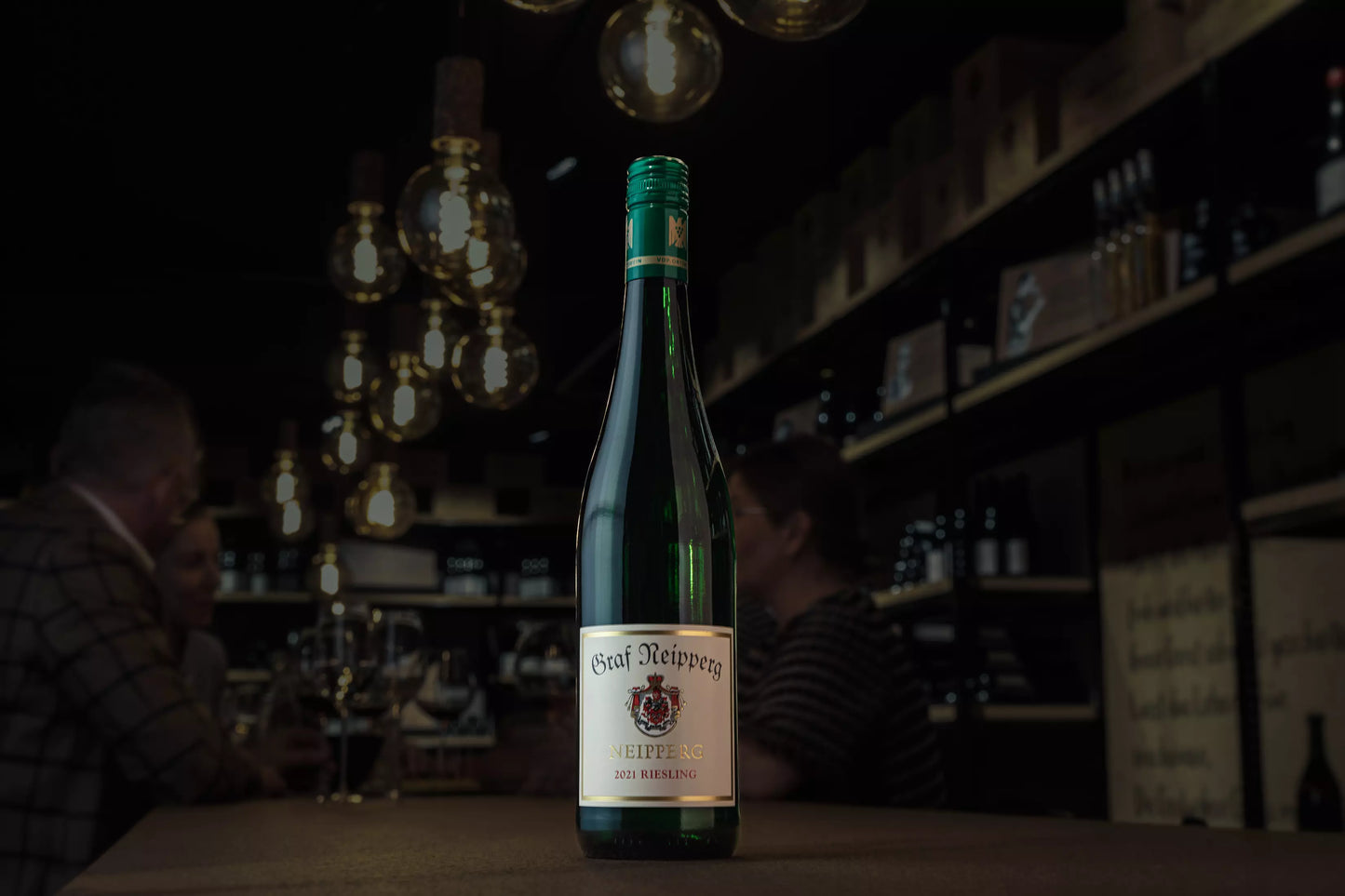 Dunkle Vinothek Hauser mit einer Flasche Neipperg Riesling VDP.Ortswein vom Weingut Graf Neipperg im Fokus auf dem Tisch.