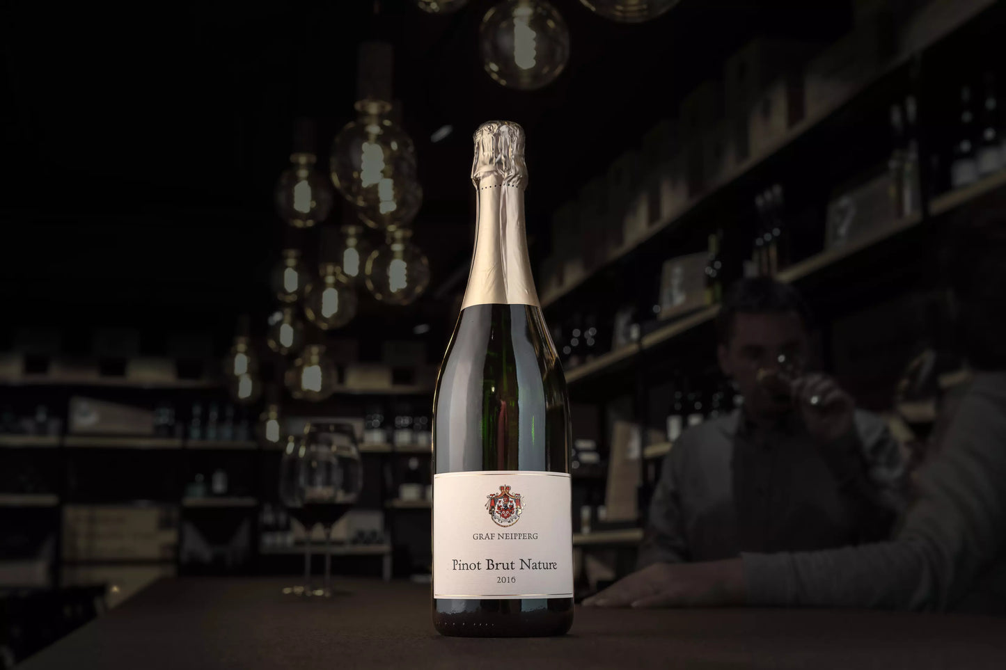 Pinot Brut Nature vom Weingut Graf Neipperg auf dem Tisch in der dunklen Vinothek Hauser.