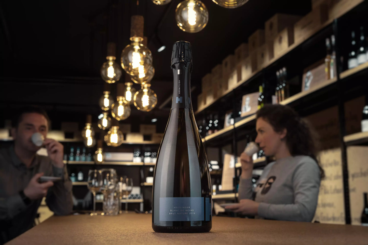 Flasche Blanc de Noirs Brut Nature vom Weingut Heitlinger auf dem Tisch in der Vinothek Hauser.