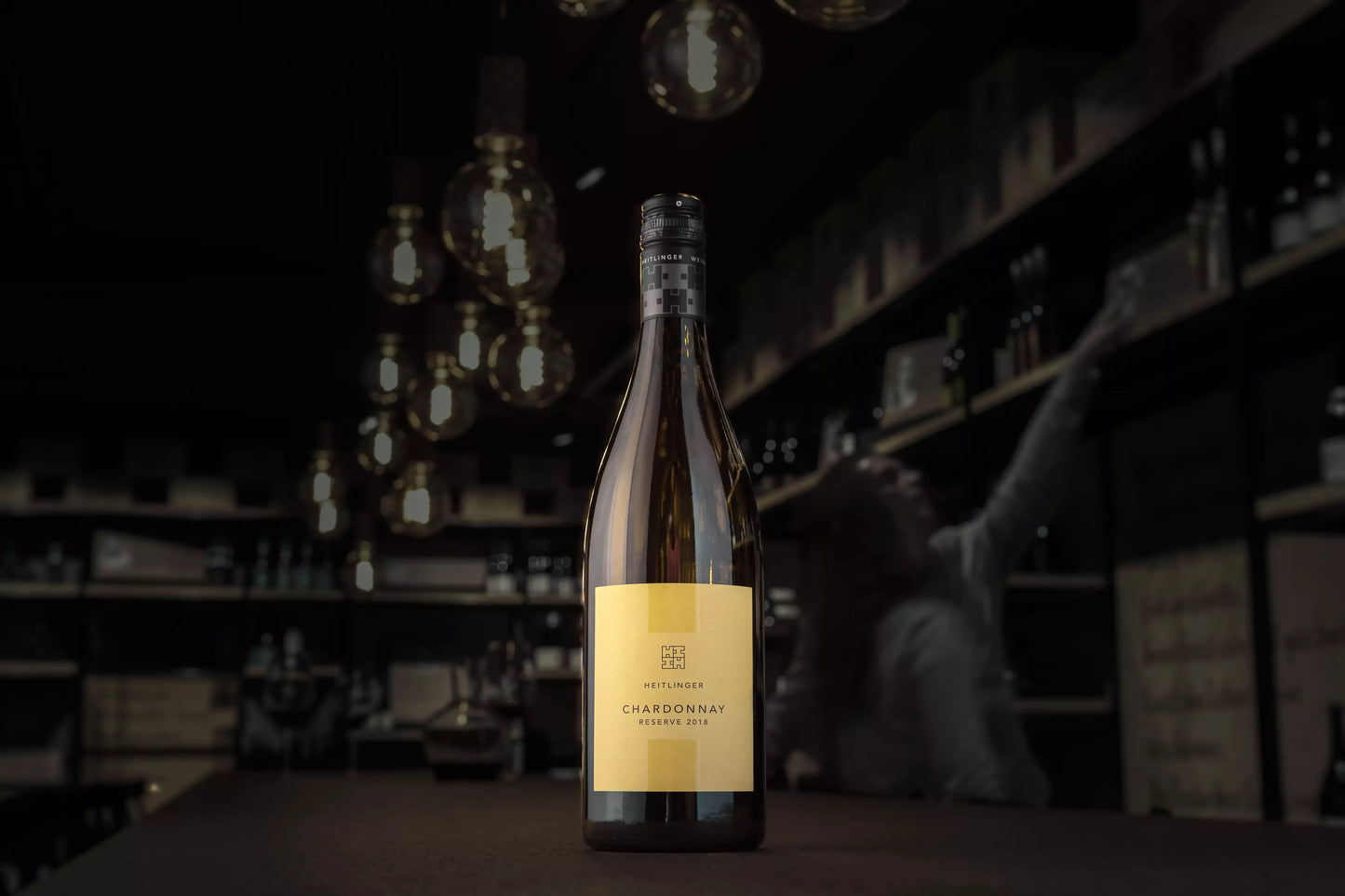 Chardonnay Reserve vom Weingut Heitlinger auf dem Tisch in der dunklen Vinothek Hauser.