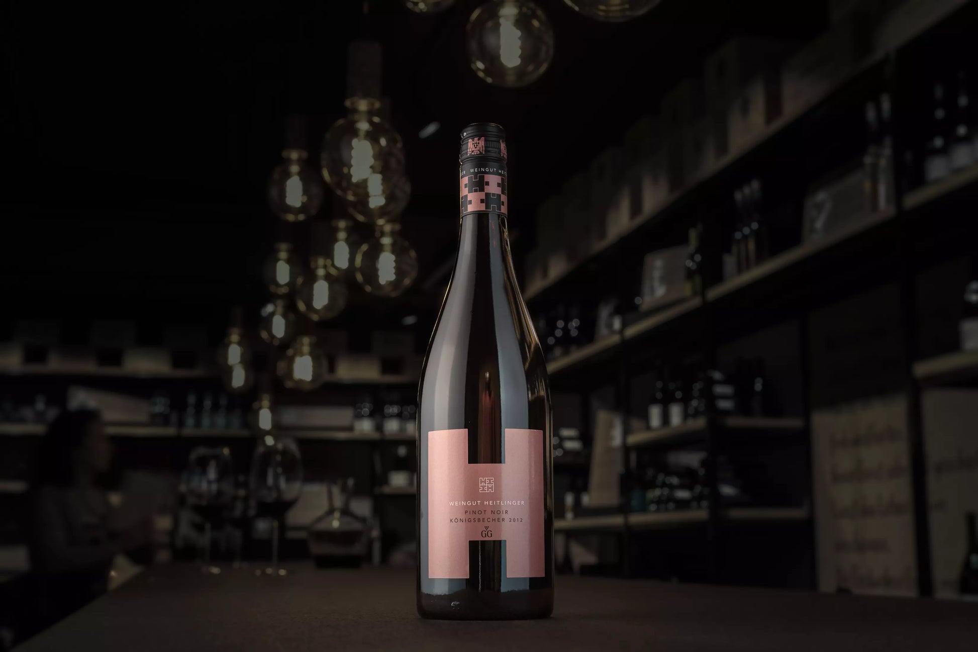 Königsbecher Pinot Noir VDP.GG vom Weingut Heitlinger auf dem Tisch in der dunklen Vinothek Hauser.
