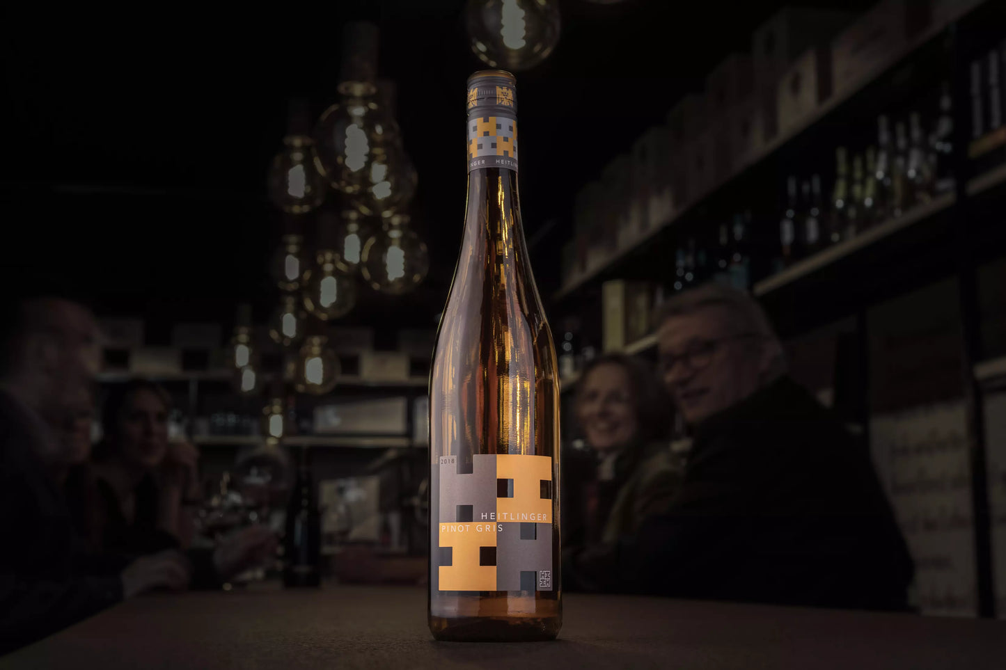 Flasche Pinot Gris VDP.Gutswein vom Weingut Heitlinger auf dem Tisch in der dunklen Vinothek Hauser.