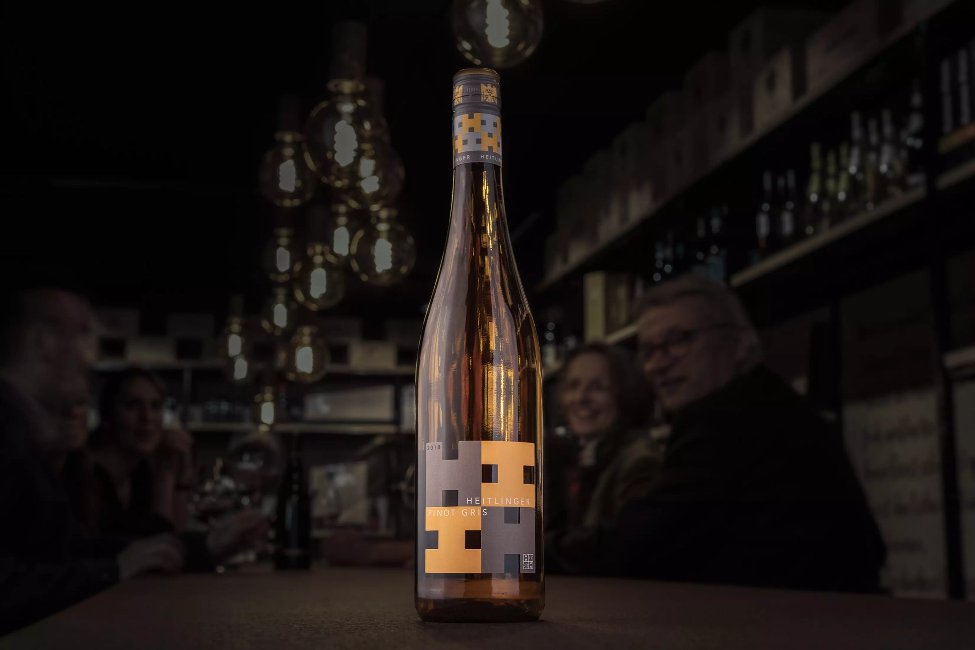 Flasche Pinot Gris VDP.Gutswein vom Weingut Heitlinger auf dem Tisch in der dunklen Vinothek Hauser.