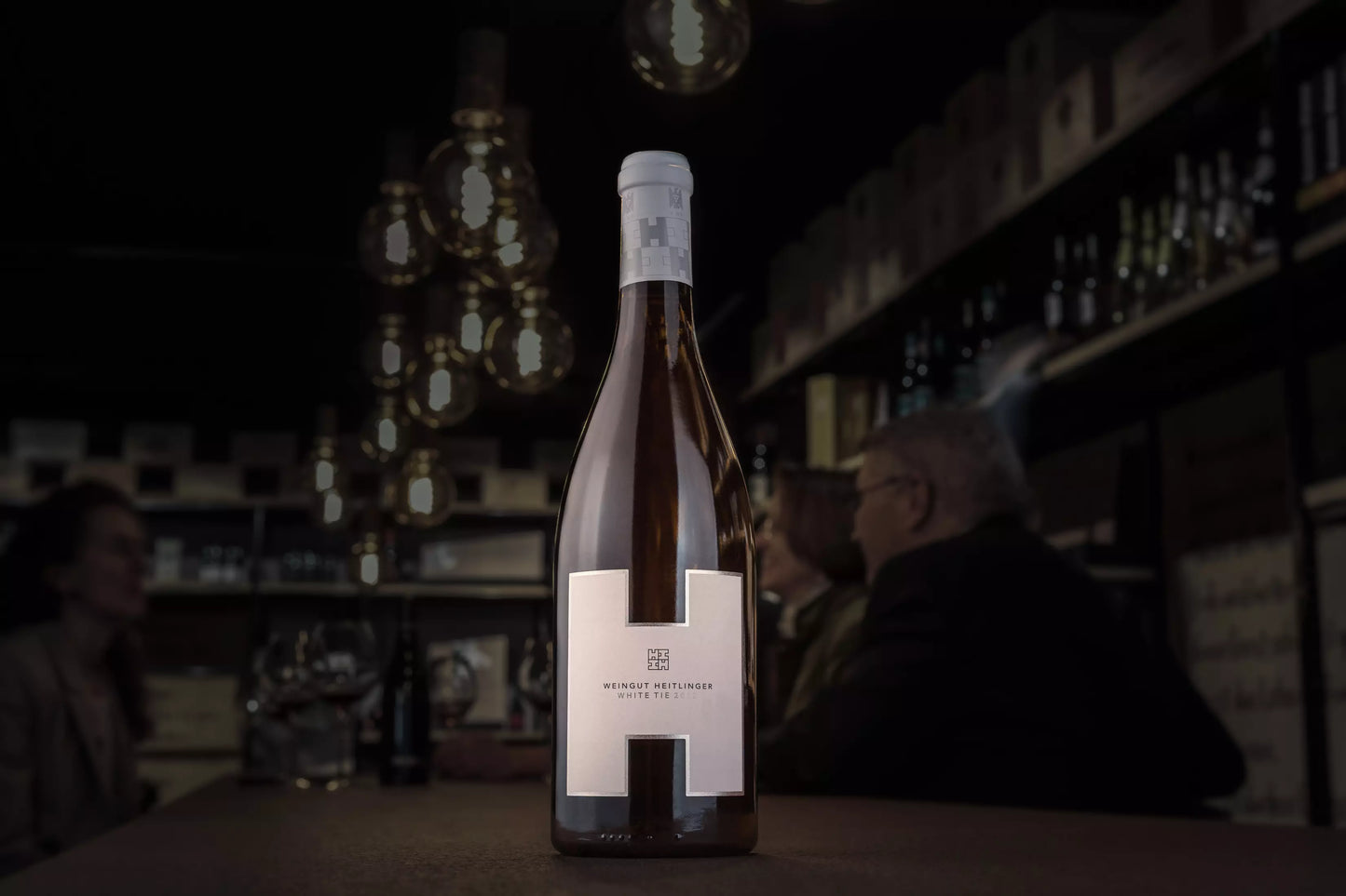 White Tie vom Weingut Heitlinger in der dunklen Vinothek Hauser auf dem Tisch.