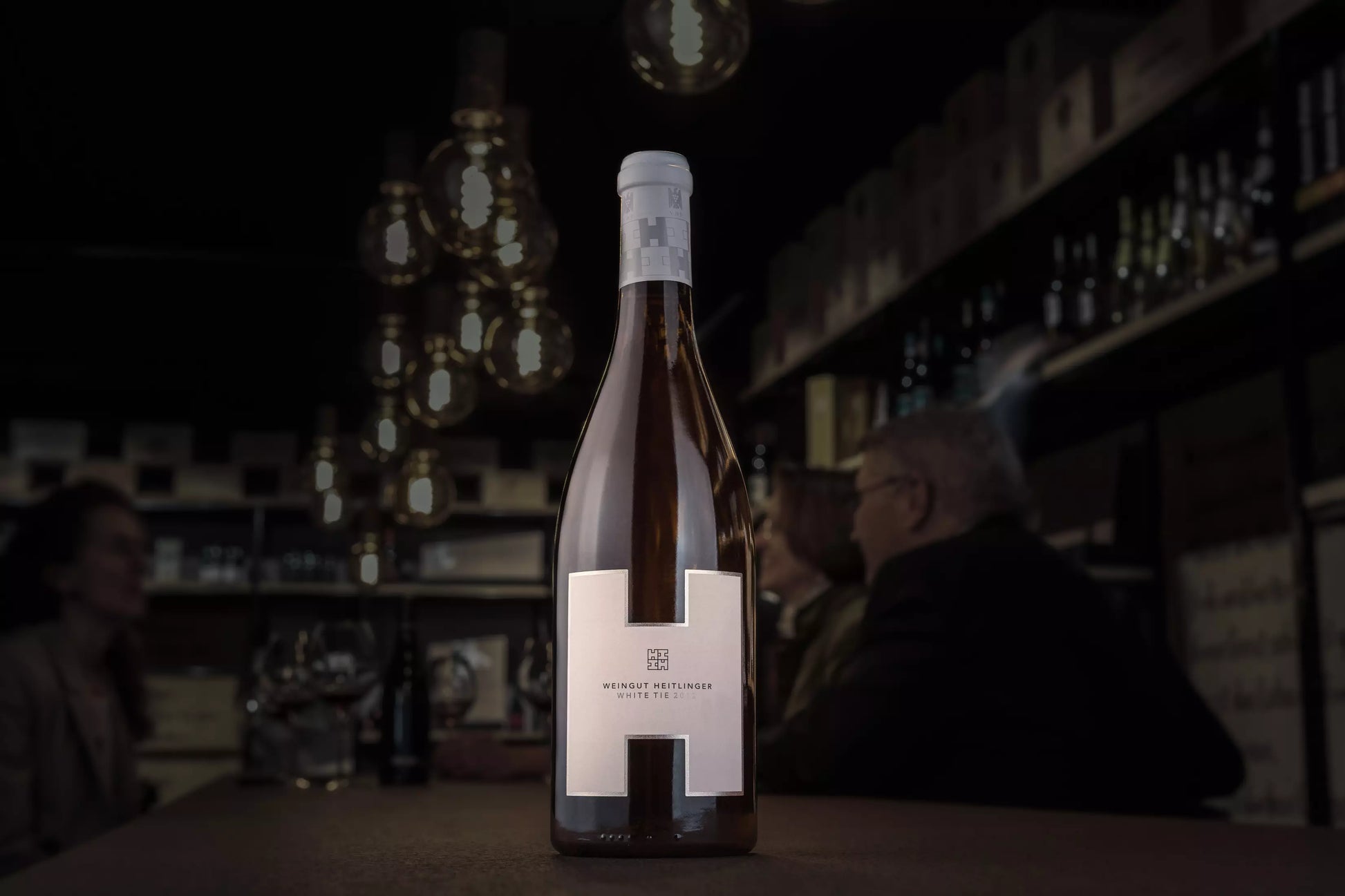 White Tie vom Weingut Heitlinger in der dunklen Vinothek Hauser auf dem Tisch.