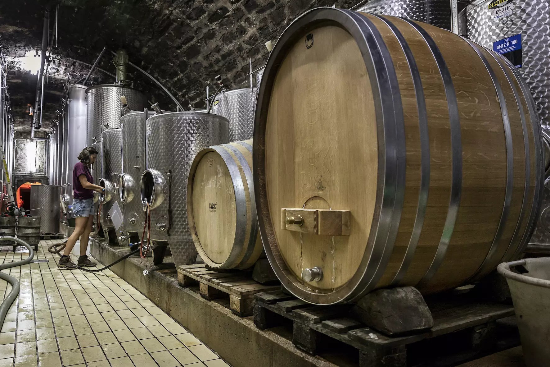 Keller vom Weingut Laura Seufert mit Holzfässern und Stahltanks, an denen Laura Seufert arbeitet.