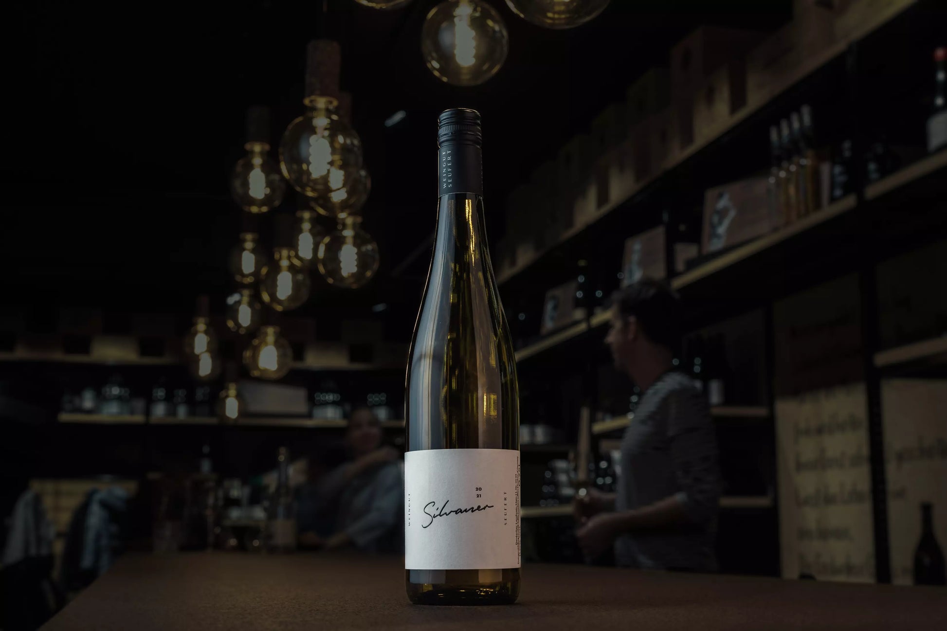 Silvaner von der Steillage vom Weingut Laura Seufert in der dunklen Vinothek Hauser auf dem Tisch.