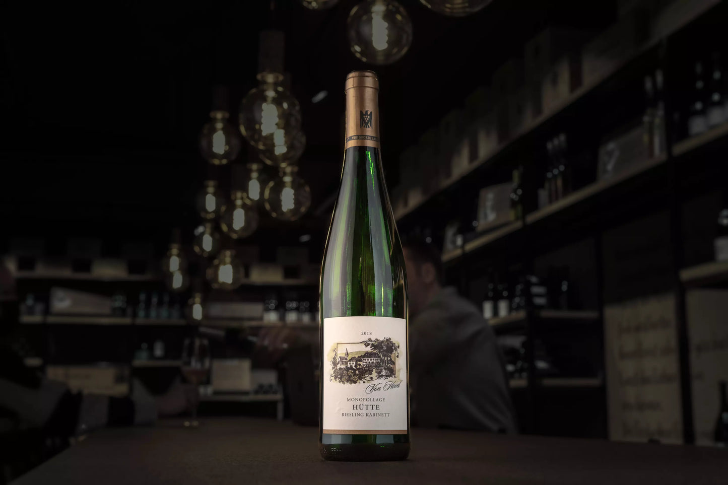 Flasche Oberemmeler Hütte Riesling Kabninett vom Weingut von Hövel auf dem Tisch in der dunklen Vinothek Hauser.