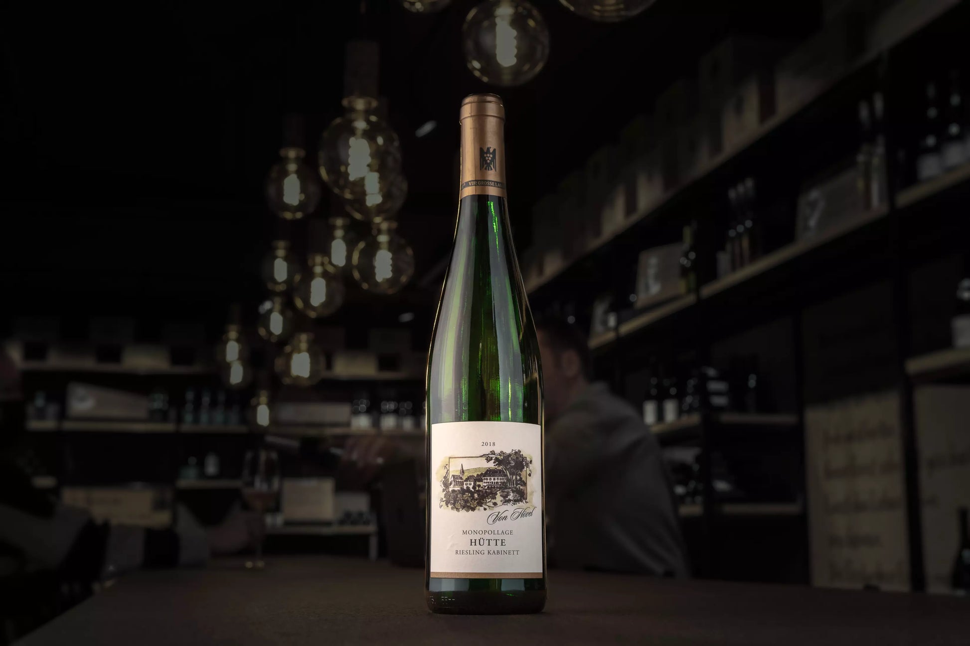Flasche Oberemmeler Hütte Riesling Kabninett vom Weingut von Hövel auf dem Tisch in der dunklen Vinothek Hauser.