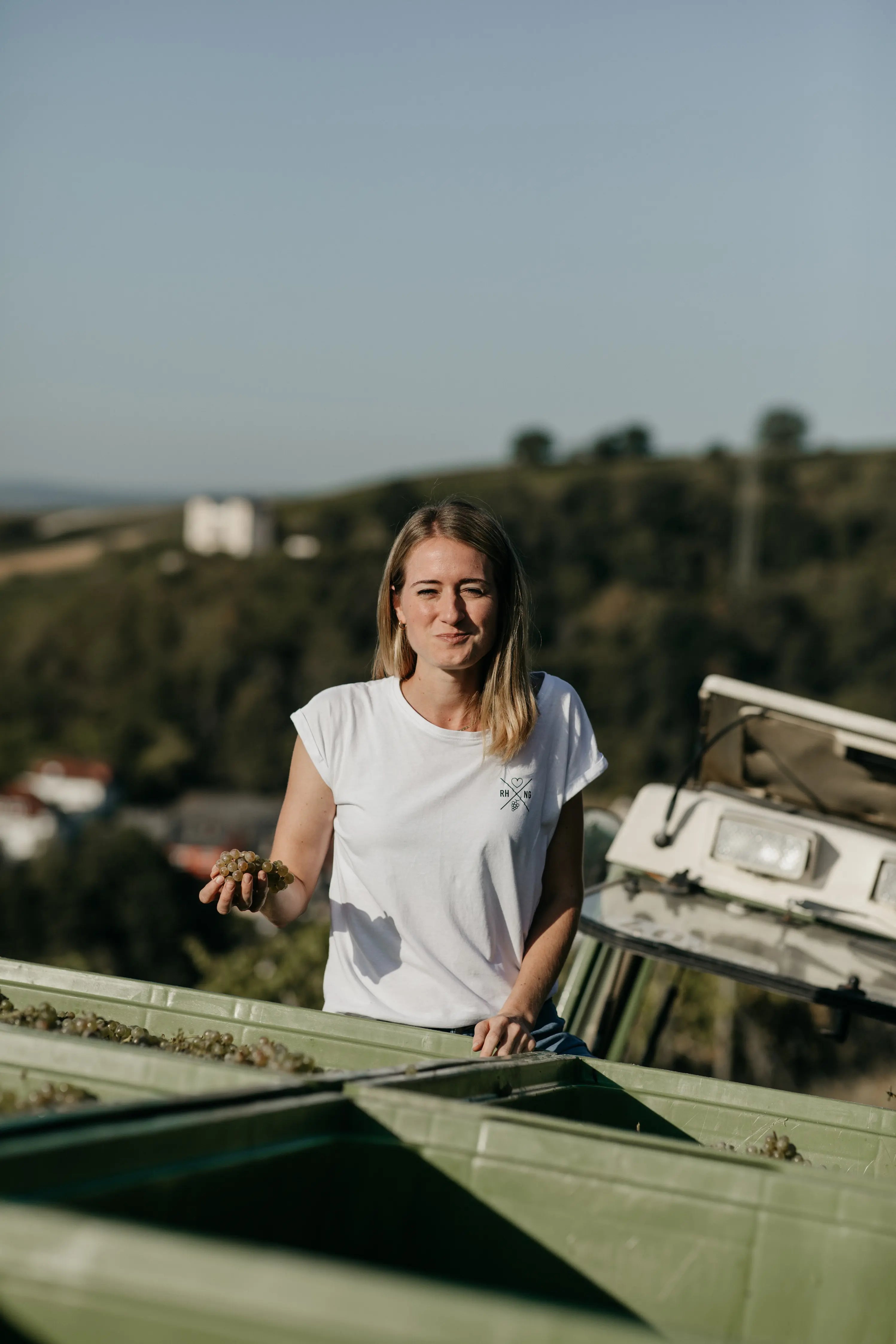 Julia Seyffardt bei der Ernte des Weingut Diefenhardt mit Trauben in der Hand.