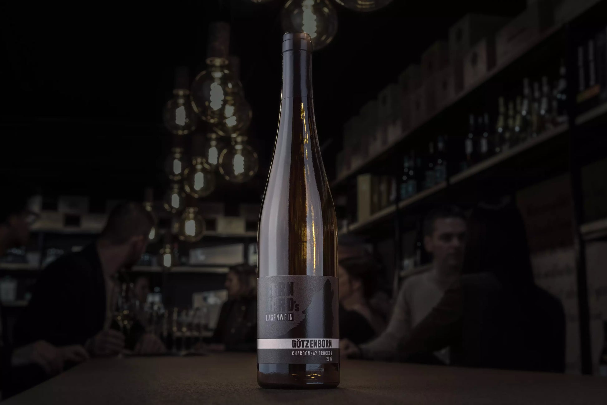 Flasche Götzenborn Chardonnay vom Weingut Bernhard auf dem Tisch in der dunklen Vinothek Hauser.