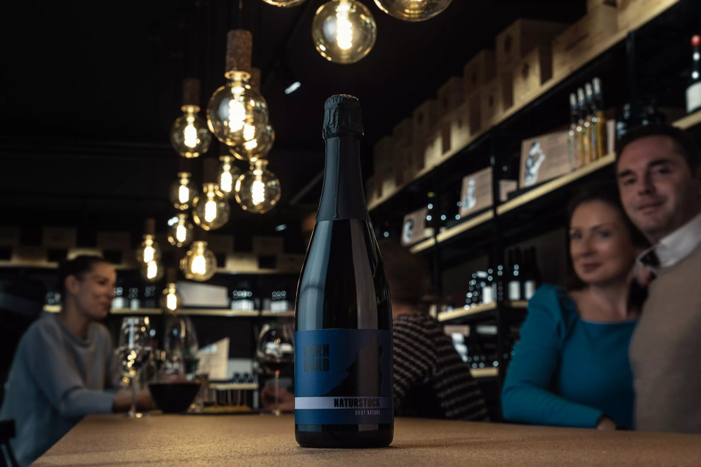 Flasche Naturstück Brut Nature in der Vinothek Hauser auf dem Tisch.