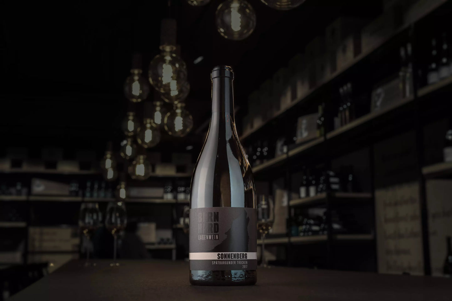 Flasche Sonnenberg Spätburgunder in der dunklein Vinothek auf dem Tisch.