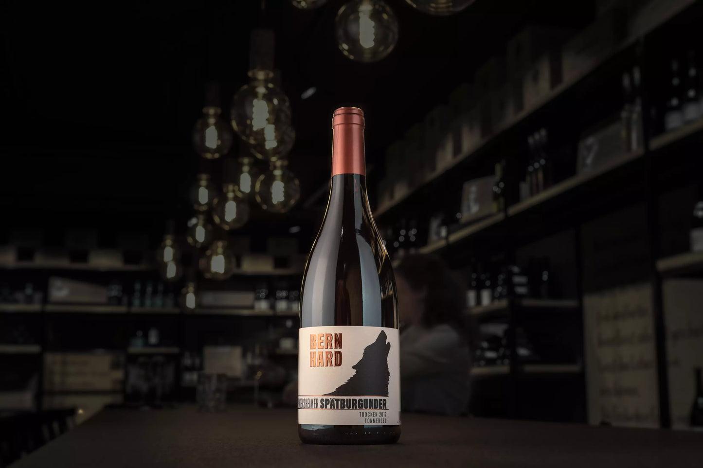 Flasche Vendersheimer Spätburgunder vom Weingut Bernhard auf dem Tisch in der dunklen Vinothek Hauser.